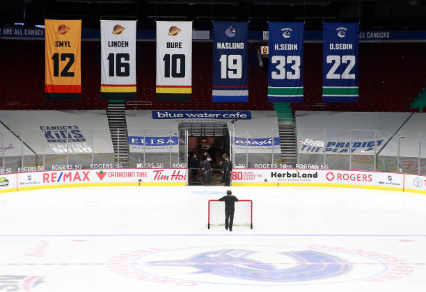 VANCOUVER, BC - MARCH 31: A rink attendant pushes a game net off the ice after the NHL game between the Calgary Flames and the Vancouver Canucks was postponed due to a positive COVID test result of a player at Rogers Arena on March 31, 2021 in Vancouver, British Columbia, Canada.  (Photo by Jeff Vinnick/NHLI via Getty Images)