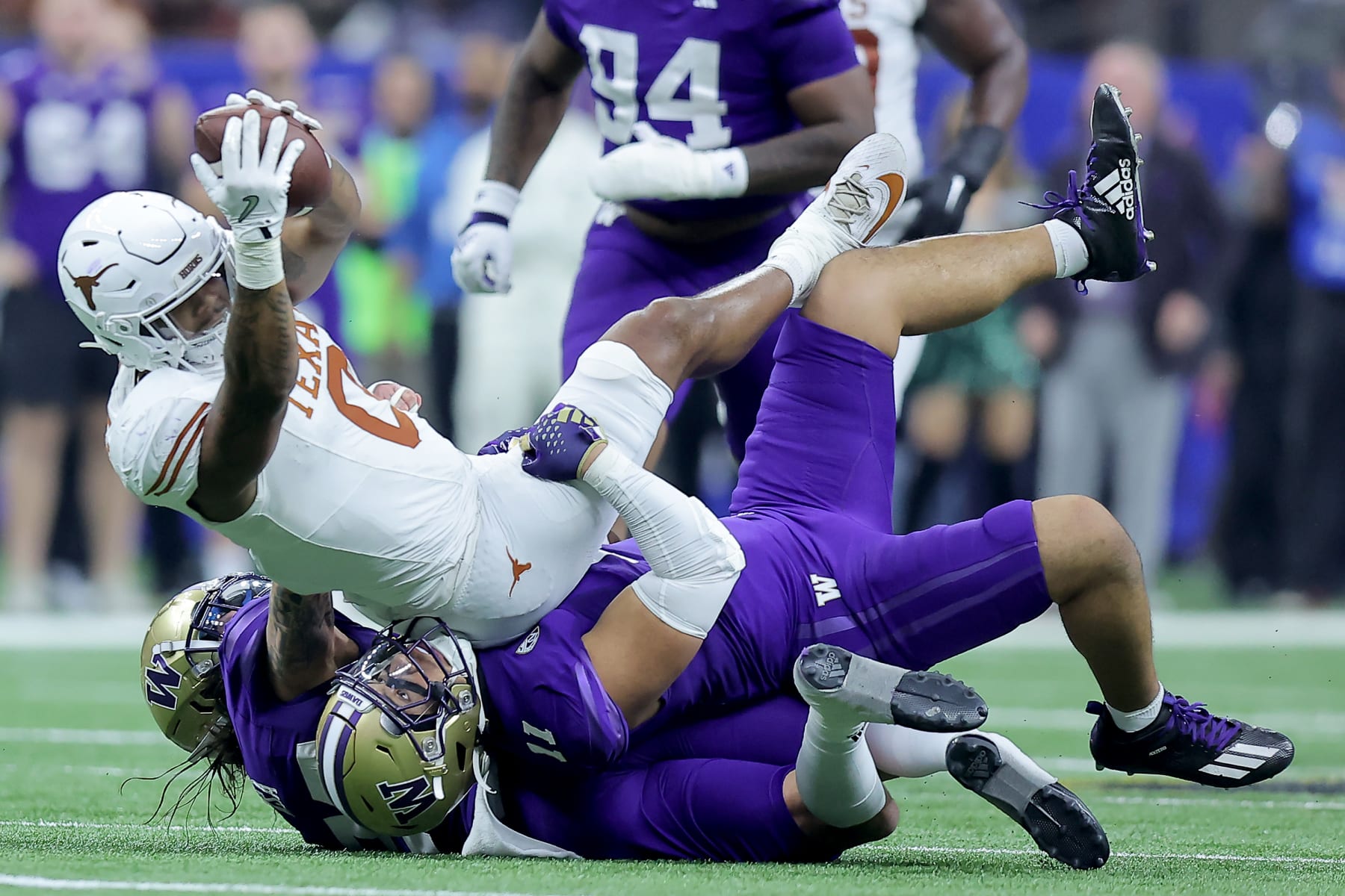 NEW ORLEANS, LOUISIANA - JANUARY 01: Ja'Tavion Sanders #0 of the Texas Longhorns is tackled by Alphonzo Tuputala #11 and Asa Turner #20 of the Washington Huskies after a catch during the second quarter during the CFP Semifinal Allstate Sugar Bowl at Caesars Superdome on January 01, 2024 in New Orleans, Louisiana. (Photo by Jonathan Bachman/Getty Images)