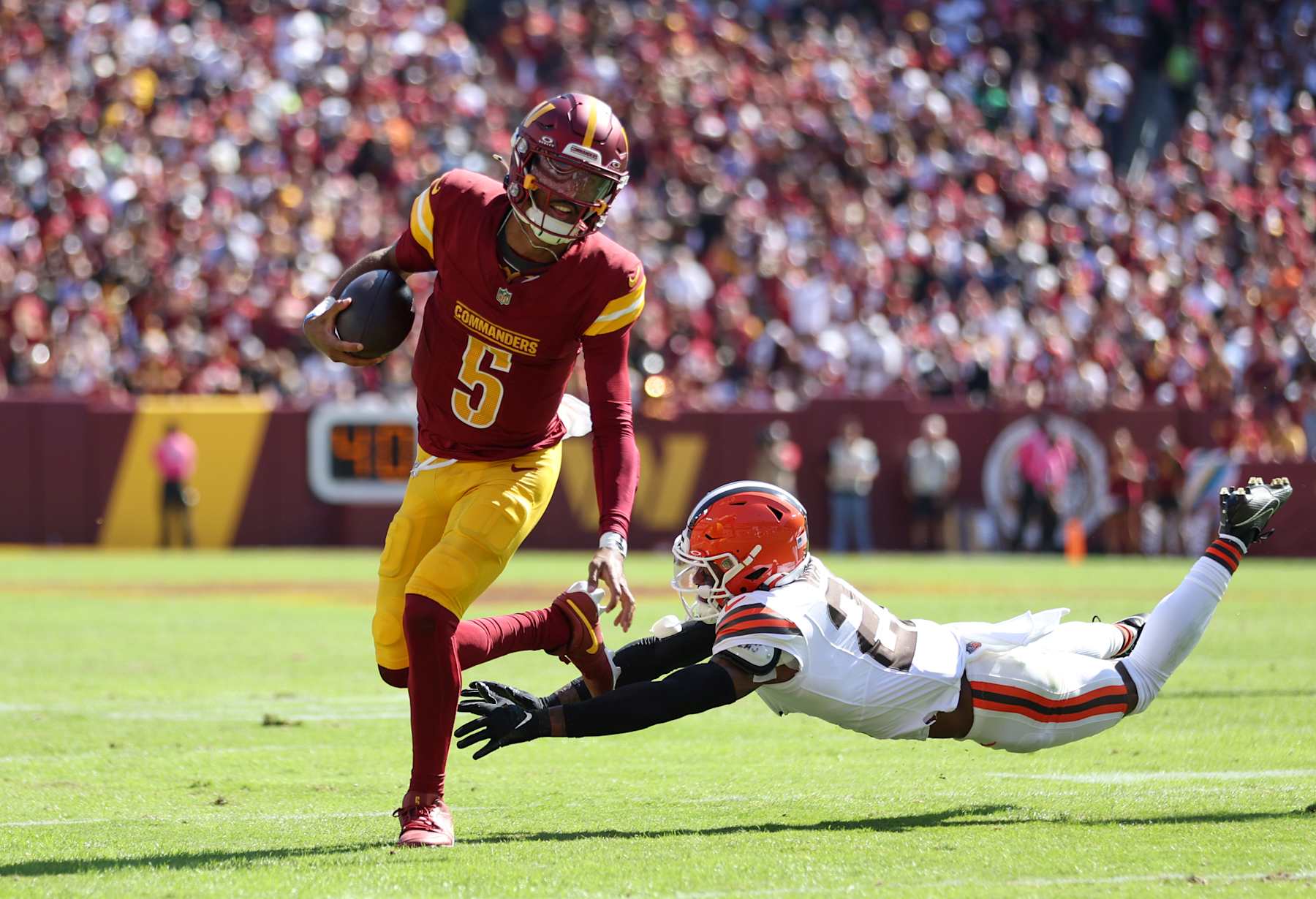 LANDOVER, MARYLAND - OCTOBER 06: Jayden Daniels #5 of the Washington Commanders runs the ball as Denzel Ward #21 of the Cleveland Browns attempts to tackle during the first half at FedExField on October 06, 2024 in Landover, Maryland. (Photo by Patrick Smith/Getty Images)