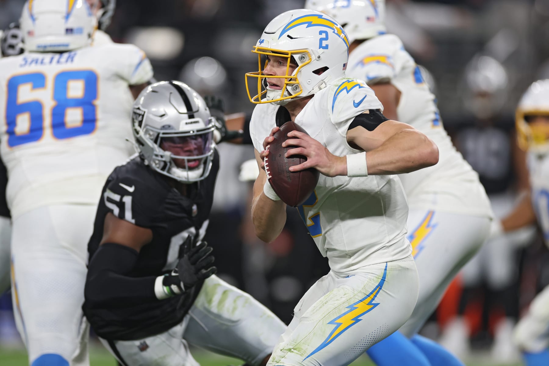 LAS VEGAS, NEVADA - DECEMBER 14: Quarterback Easton Stick #2 of the Los Angeles Chargers looks to pass in front of defensive end Malcolm Koonce #51 of the Las Vegas Raiders during the second quarter at Allegiant Stadium on December 14, 2023 in Las Vegas, Nevada. (Photo by Sean M. Haffey/Getty Images)