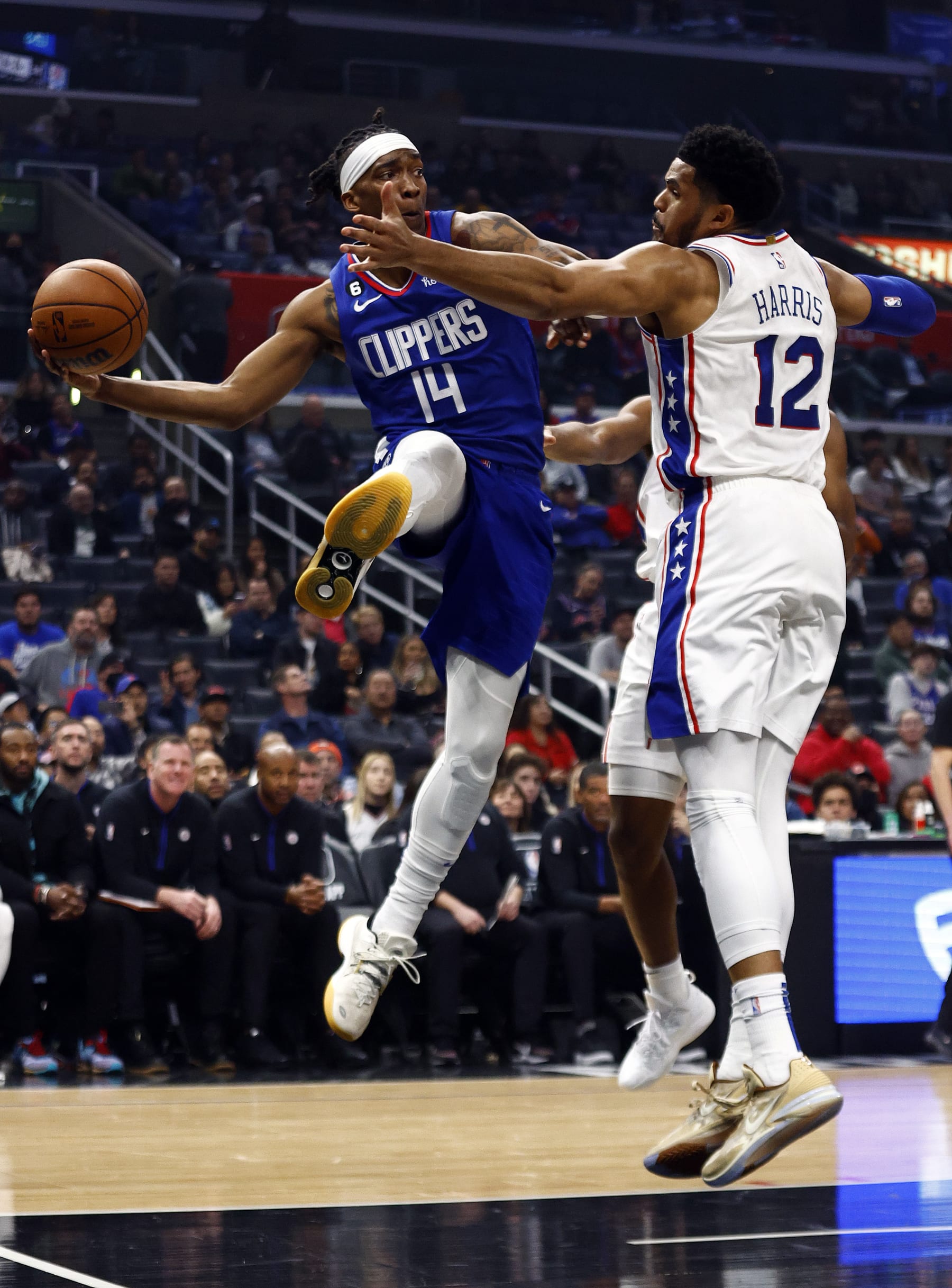 Terance Mann throws a pass around Tobias Harris