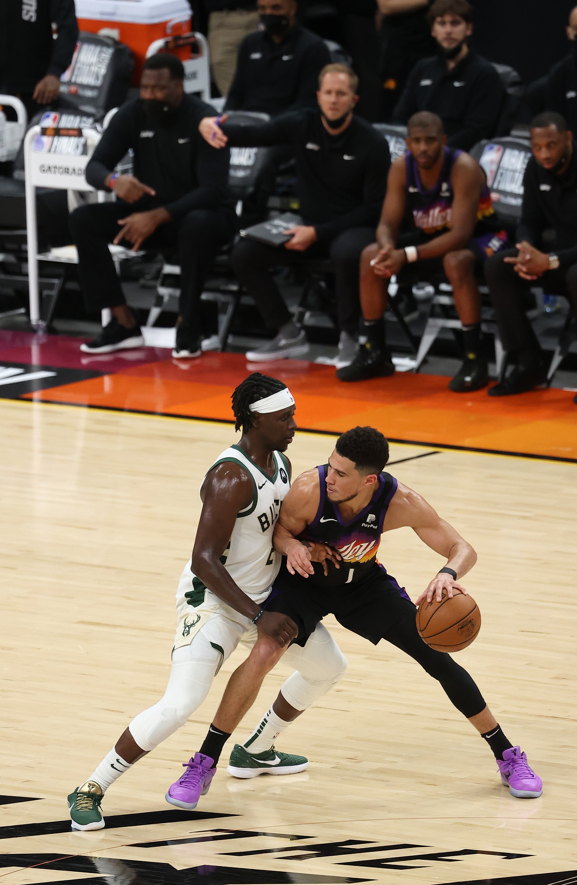 PHOENIX, ARIZONA - JULY 17: Jrue Holiday #21 of the Milwaukee Bucks defends as Devin Booker #1 of the Phoenix Suns brings the ball up court during the second half in Game Five of the NBA Finals at Footprint Center on July 17, 2021 in Phoenix, Arizona. NOTE TO USER: User expressly acknowledges and agrees that, by downloading and or using this photograph, User is consenting to the terms and conditions of the Getty Images License Agreement.  (Photo by Ronald Martinez/Getty Images)