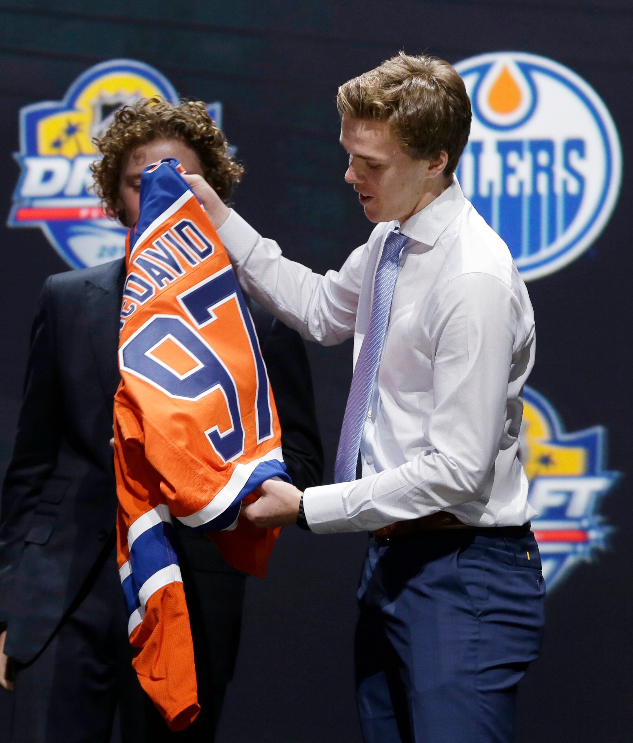 Connor McDavid prepares to put on an Edmonton Oilers sweater after being picked first overall by the Oilers during the first round of the NHL hockey draft, Friday, June 26, 2015, in Sunrise, Fla. (AP Photo/Alan Diaz)
