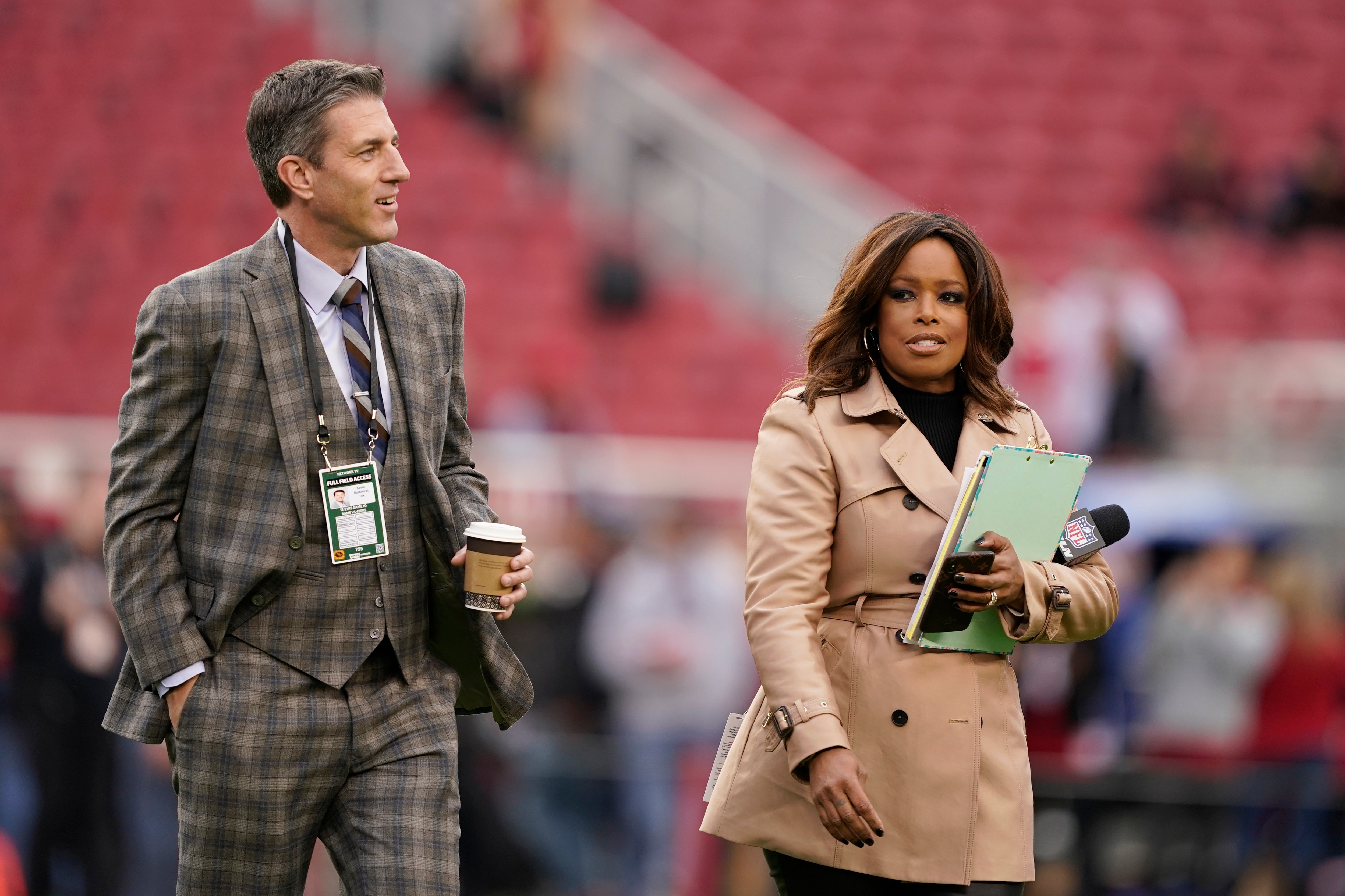 Reporters Kevin Burkhardt and Pam Oliver walk on the field before an NFL football game between the San Francisco 49ers and the Los Angeles Rams in Santa Clara, Calif., Saturday, Dec. 21, 2019. (AP Photo/Tony Avelar)