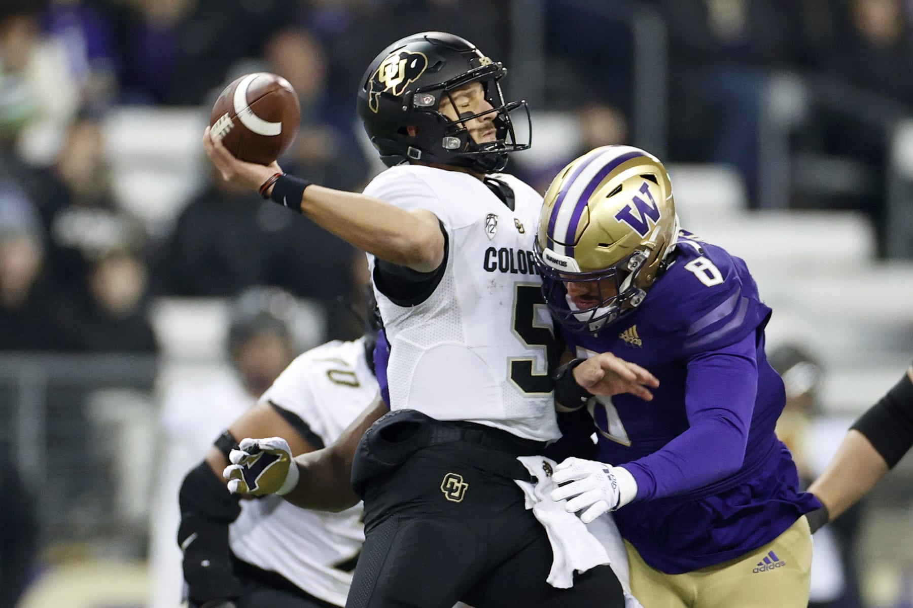 SEATTLE, WASHINGTON - NOVEMBER 19: J.T. Shrout #5 of the Colorado Buffaloes is hit by Bralen Trice #8 of the Washington Huskies during the third quarter at Husky Stadium on November 19, 2022 in Seattle, Washington. (Photo by Steph Chambers/Getty Images)