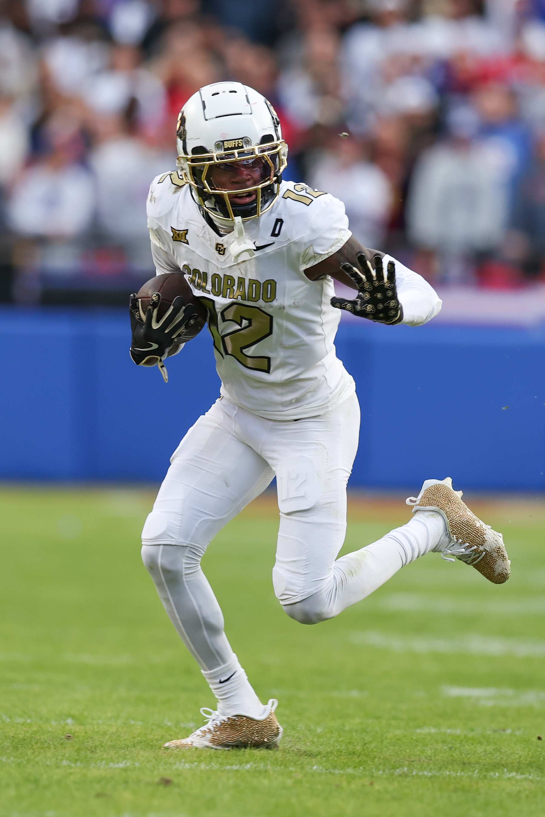 KANSAS CITY, MO - NOVEMBER 23: Colorado Buffaloes wide receiver Travis Hunter (12) looks to stiff arm a defender during a catch and run in the second quarter of a Big 12 game between the Colorado Buffaloes and Kansas Jayhawks on November 23, 2024 at GEHA Field at Arrowhead Stadium in Kansas City, MO. (Photo by Scott Winters/Icon Sportswire via Getty Images)
