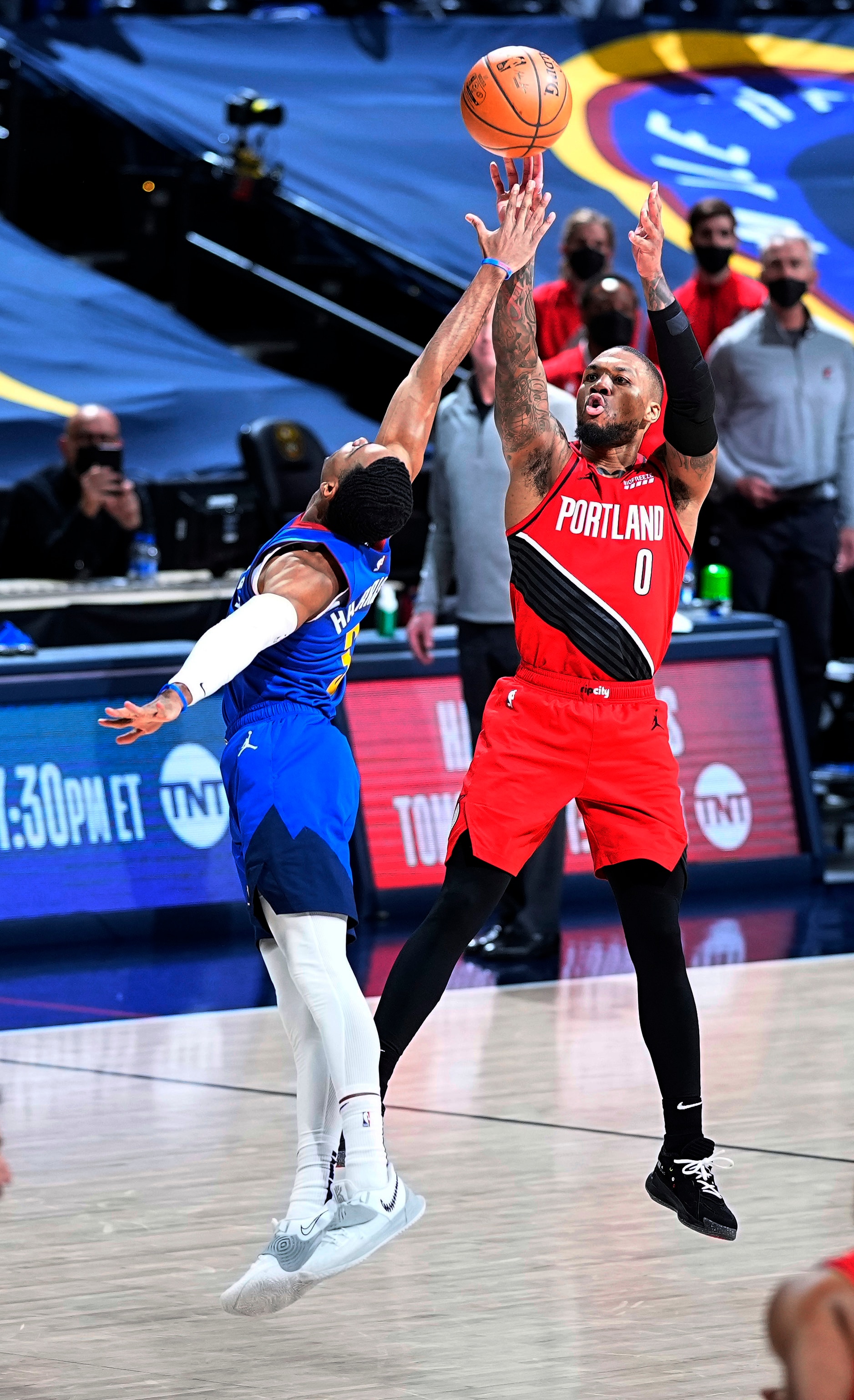 Portland Trail Blazers guard Damian Lillard (0) shoots a 3-point basket against Denver Nuggets guard Shaquille Harrison (3) to send Game 5 of a first-round NBA basketball playoff series into a second overtime, Tuesday, June 1, 2021, in Denver. (AP Photo/Jack Dempsey)