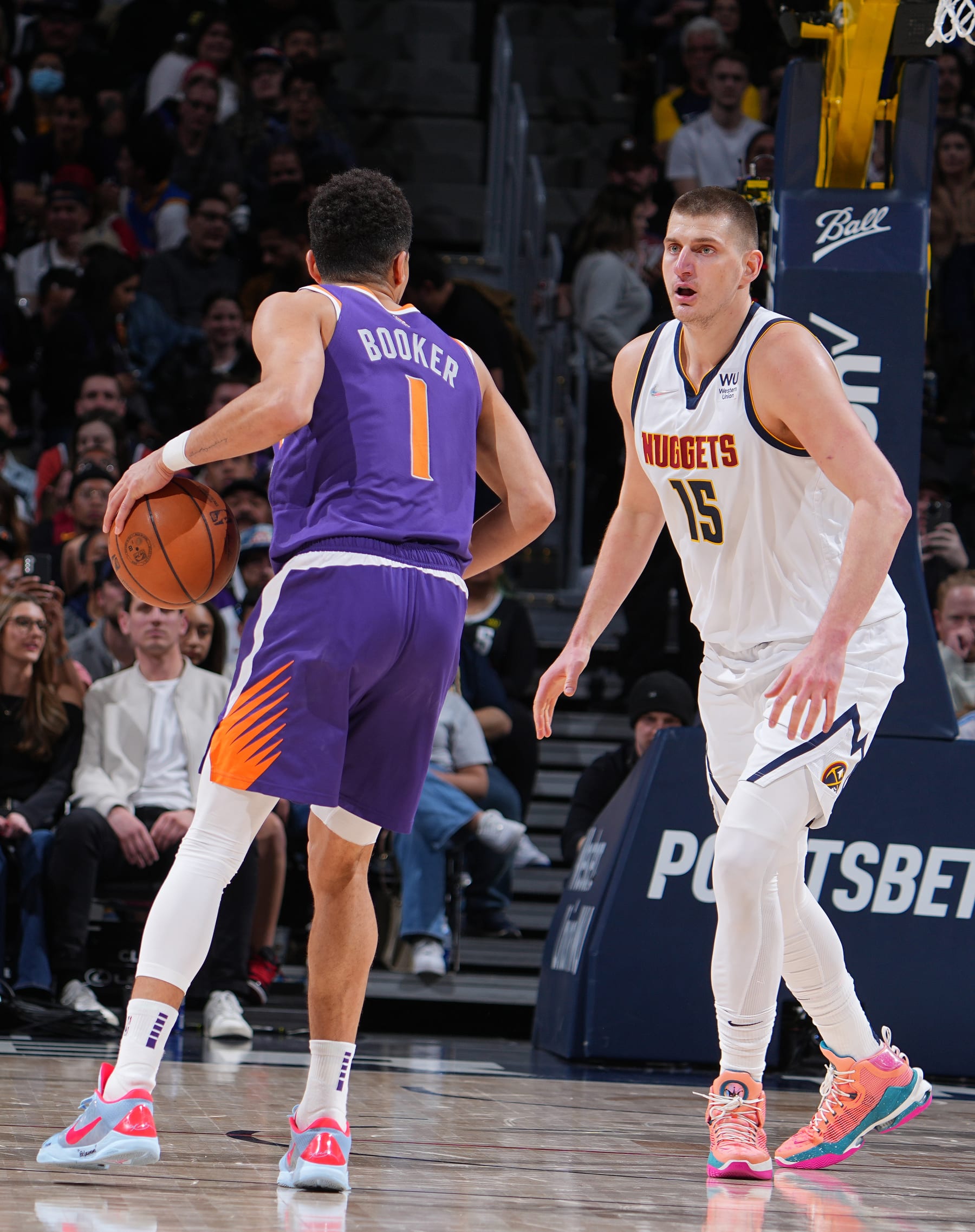 DENVER, CO - MARCH 24: Nikola Jokic #15 of the Denver Nuggets plays defense on Devin Booker #1 of the Phoenix Suns during the game on March 24, 2022 at the Ball Arena in Denver, Colorado. NOTE TO USER: User expressly acknowledges and agrees that, by downloading and/or using this Photograph, user is consenting to the terms and conditions of the Getty Images License Agreement. Mandatory Copyright Notice: Copyright 2022 NBAE (Photo by Bart Young/NBAE via Getty Images) DENVER, CO - MARCH 24: Nikola Jokic #15 of the Denver Nuggets plays defense on Devin Booker #1 of the Phoenix Suns during the game on March 24, 2022 at the Ball Arena in Denver, Colorado. NOTE TO USER: User expressly acknowledges and agrees that, by downloading and/or using this Photograph, user is consenting to the terms and conditions of the Getty Images License Agreement. Mandatory Copyright Notice: Copyright 2022 NBAE (Photo by Bart Young/NBAE via Getty Images)