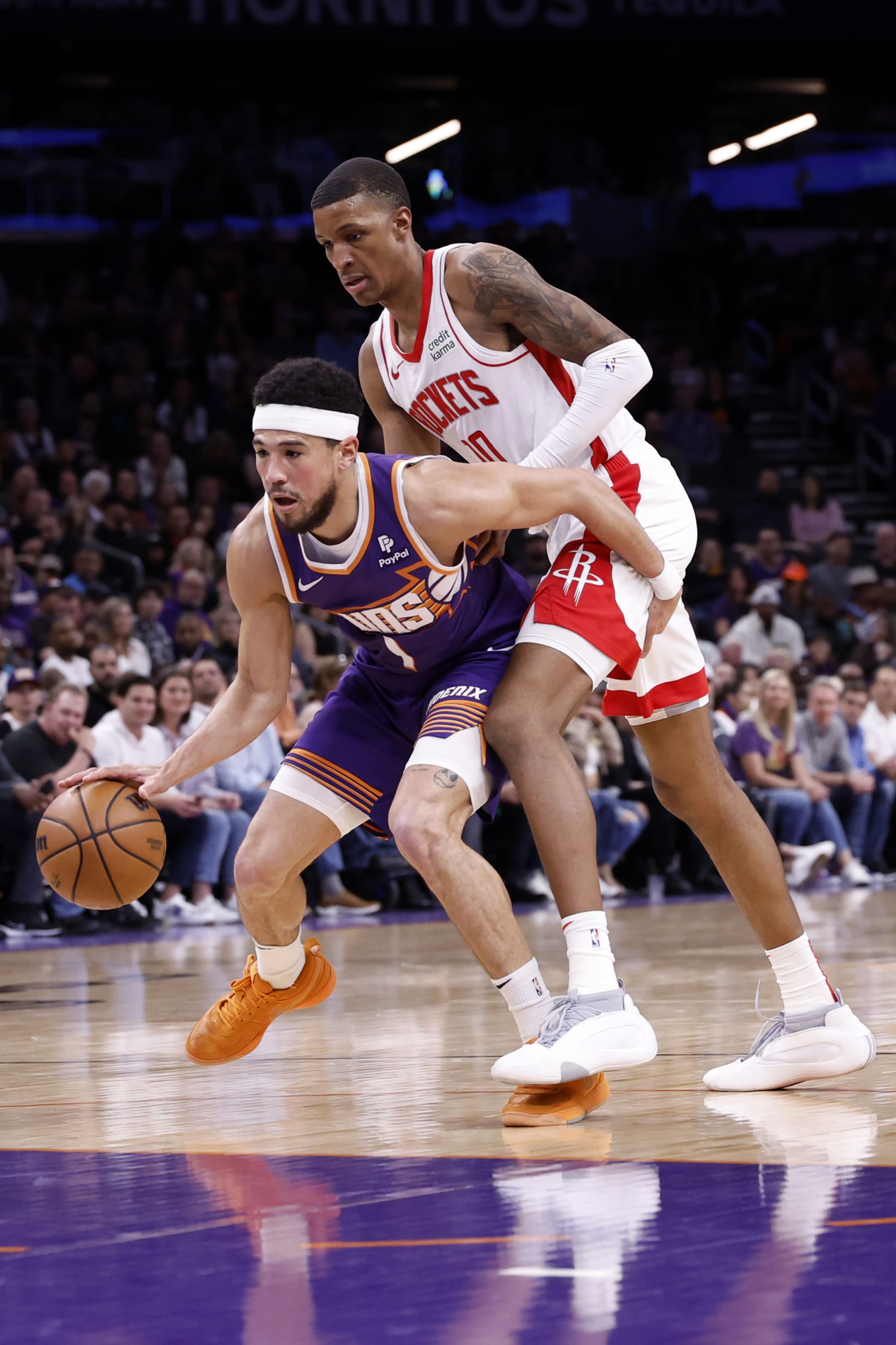 PHOENIX, ARIZONA - MARCH 02: Devin Booker #1 of the Phoenix Suns drives past Jabari Smith Jr. #10 of the Houston Rockets during the game at Footprint Center on March 02, 2024 in Phoenix, Arizona. The Rockets defeated the Suns 118-109. NOTE TO USER: User expressly acknowledges and agrees that, by downloading and or using this photograph, User is consenting to the terms and conditions of the Getty Images License Agreement.  (Photo by Chris Coduto/Getty Images)