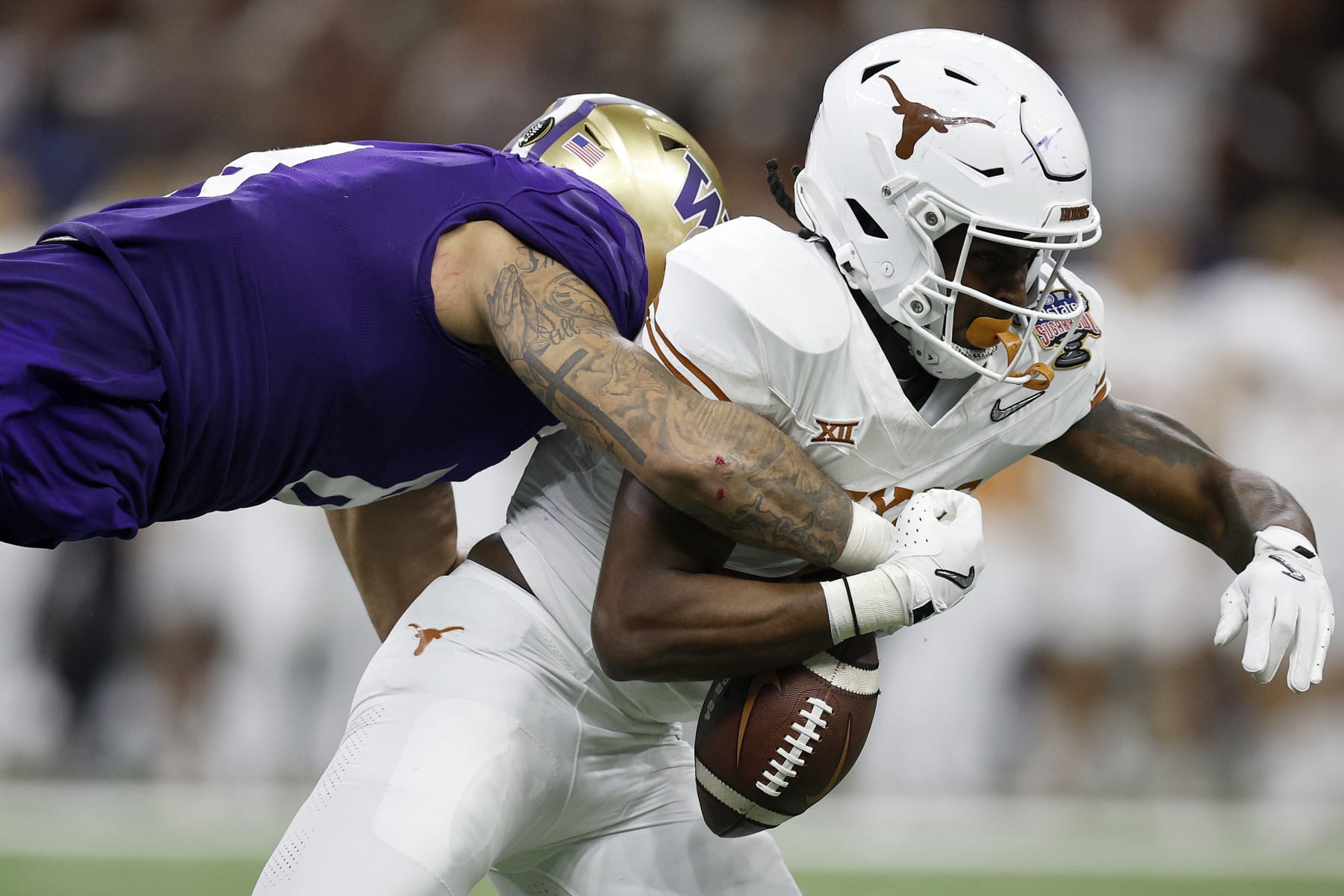 NEW ORLEANS, LOUISIANA - JANUARY 01: Bralen Trice #8 of the Washington Huskies forces a fumble against CJ Baxter #4 of the Texas Longhorns during the third quarter during the CFP Semifinal Allstate Sugar Bowl at Caesars Superdome on January 01, 2024 in New Orleans, Louisiana. (Photo by Sean Gardner/Getty Images)