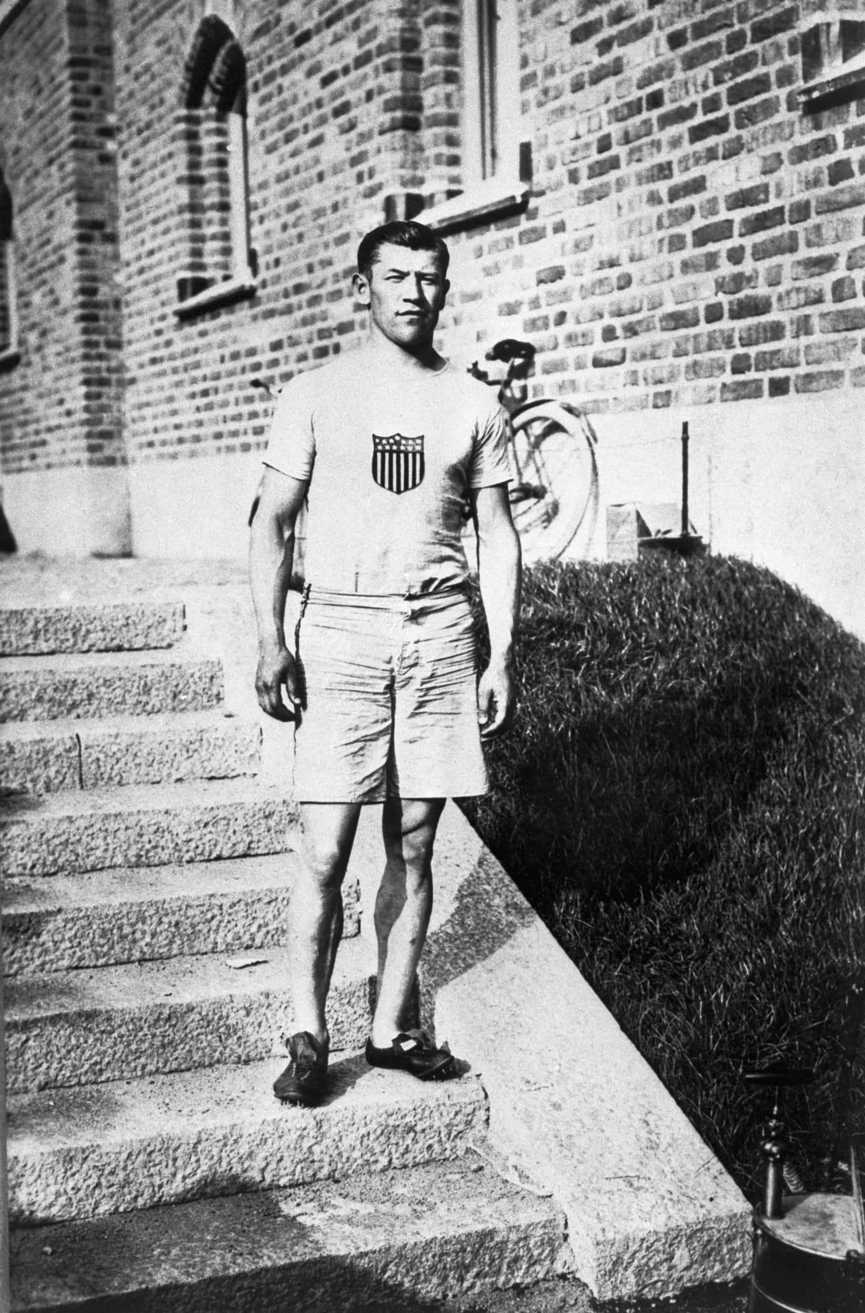 American athlete Jim Thorpe wears his Olympic uniform as he stands on a stairway in front of a building at the 1912 Summer Olympics in Stockholm, Sweden. He wins the gold medal in both the decathlon and pentathlon events at these Olympics, but in 1913 the Amateur Athletic Union strips him of his medals because of a question concerning his amateur status.