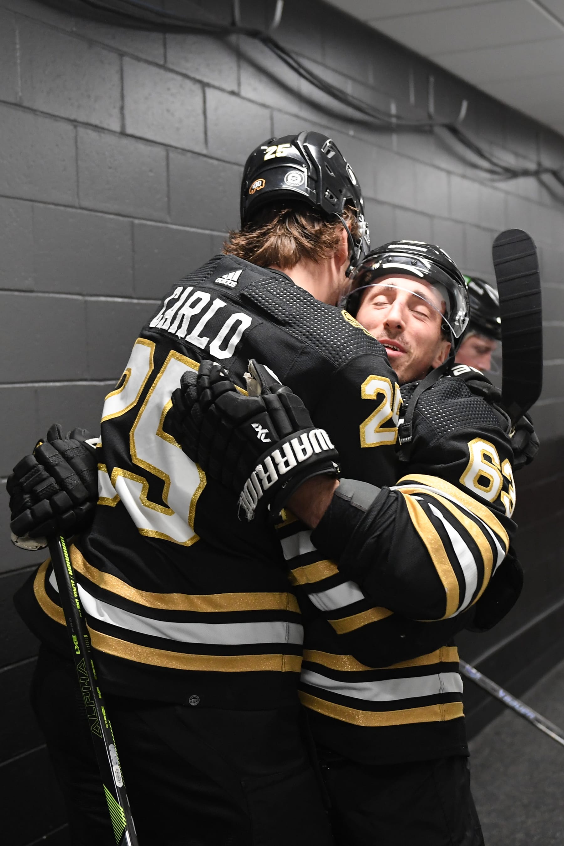 BOSTON, MASSACHUSETTS - FEBRUARY 6: Brandon Carlo #25 and Brad Marchand #63 of the Boston Bruins hug in the hallway before the game against the Calgary Flames at the TD Garden on February 6, 2024 in Boston, Massachusetts. (Photo by Steve Babineau/NHLI via Getty Images)