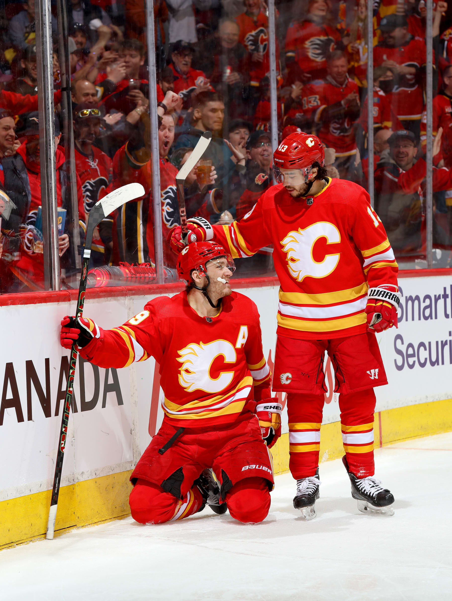 CALGARY, ALBERTA - APRIL 16: Matthew Tkachuk #19, Johnny Gaudreau #13, and teammates of the Calgary Flames celebrate a goal against the Arizona Coyotes at Scotiabank Saddledome on April 16, 2022 in Calgary, Alberta. (Photo by Gerry Thomas/NHLI via Getty Images)