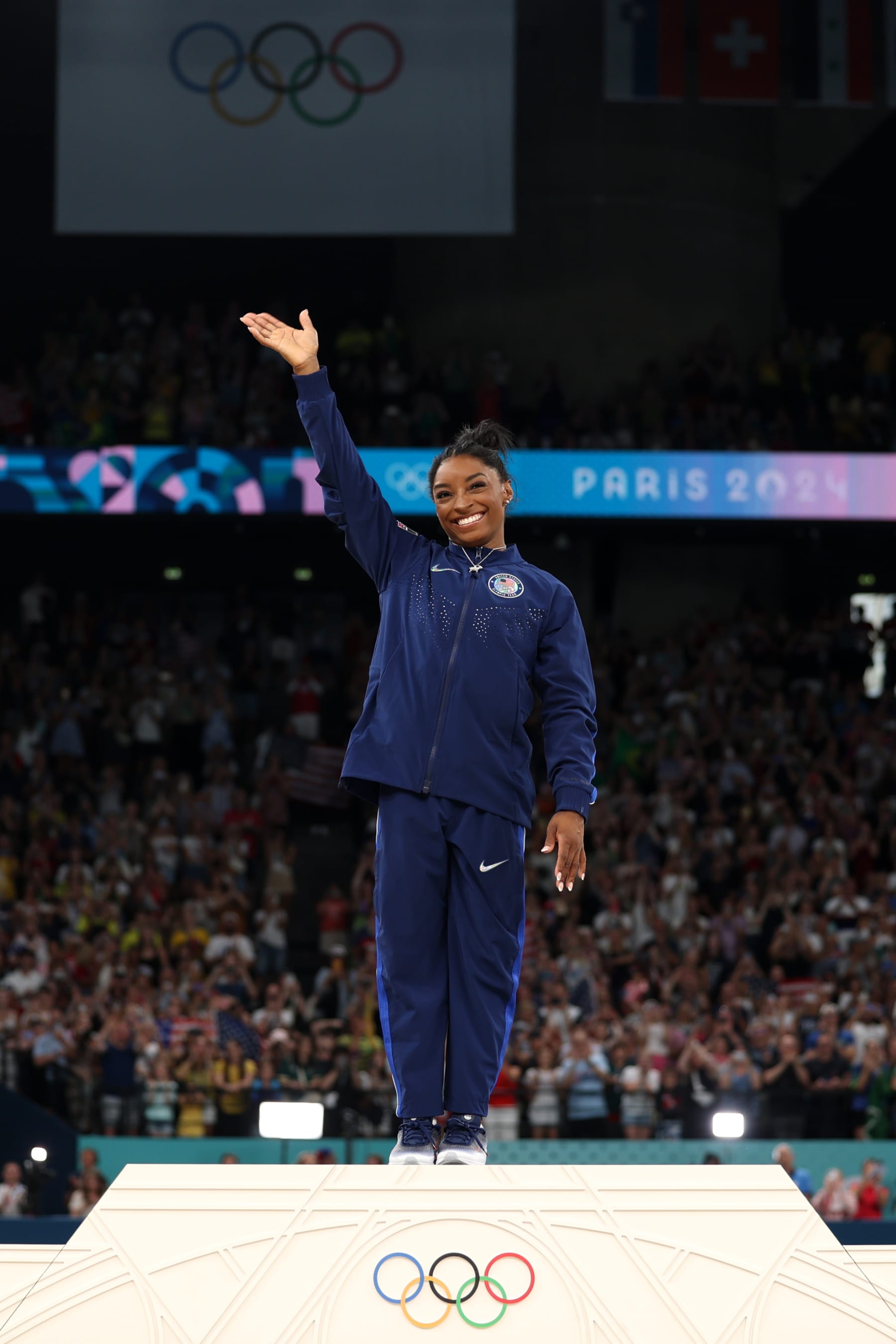 PARIS, FRANCE - AUGUST 01: Gold medalist Simone Biles of Team United States waves on the podium during the Artistic Gymnastics Women's All-Around Final medal ceremony on day six of the Olympic Games Paris 2024 at Bercy Arena on August 01, 2024 in Paris, France. (Photo by Jamie Squire/Getty Images)
