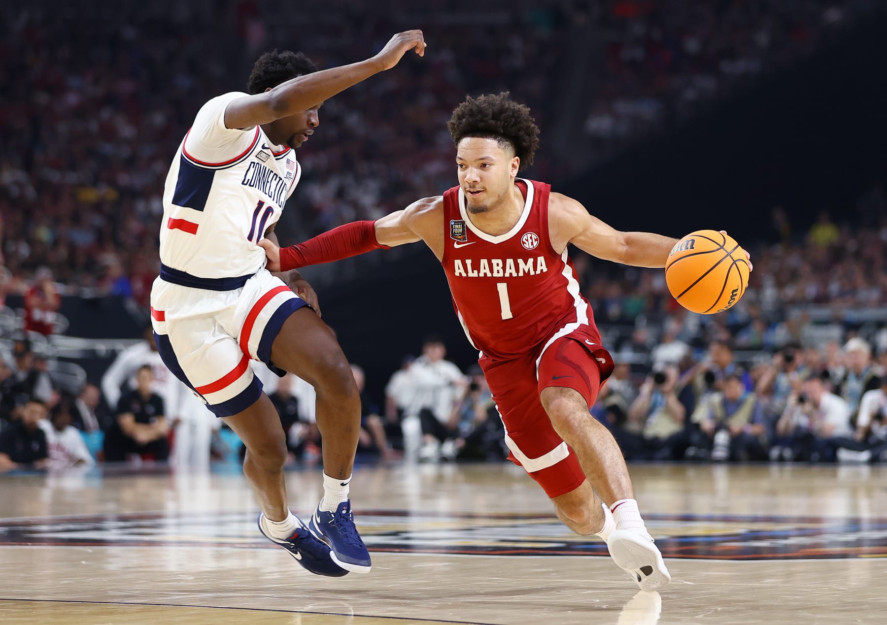 GLENDALE, ARIZONA - APRIL 06: Mark Sears #1 of the Alabama Crimson Tide dribbles the ball around Hassan Diarra #10 of the Connecticut Huskies during the first half in the NCAA Men’s Basketball Tournament Final Four semifinal game at State Farm Stadium on April 06, 2024 in Glendale, Arizona. (Photo by Jamie Schwaberow/NCAA Photos via Getty Images)