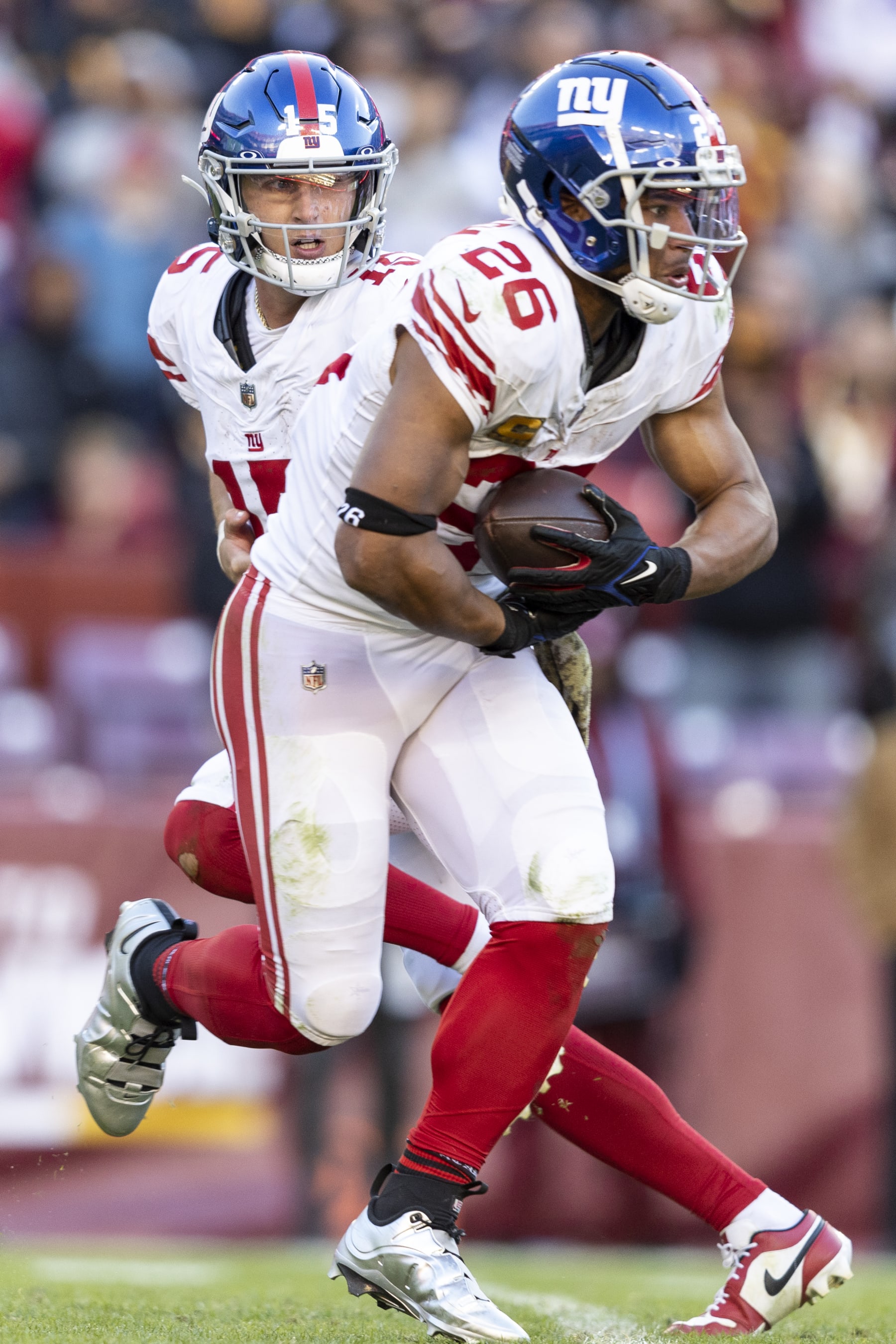 LANDOVER, MARYLAND - NOVEMBER 19: Tommy DeVito #15 of the New York Giants hands the ball off to Saquon Barkley #26 of the New York Giants during an NFL football game between the Washington Commanders and the New York Giants at FedExField on November 19, 2023 in Landover, Maryland. (Photo by Michael Owens/Getty Images)