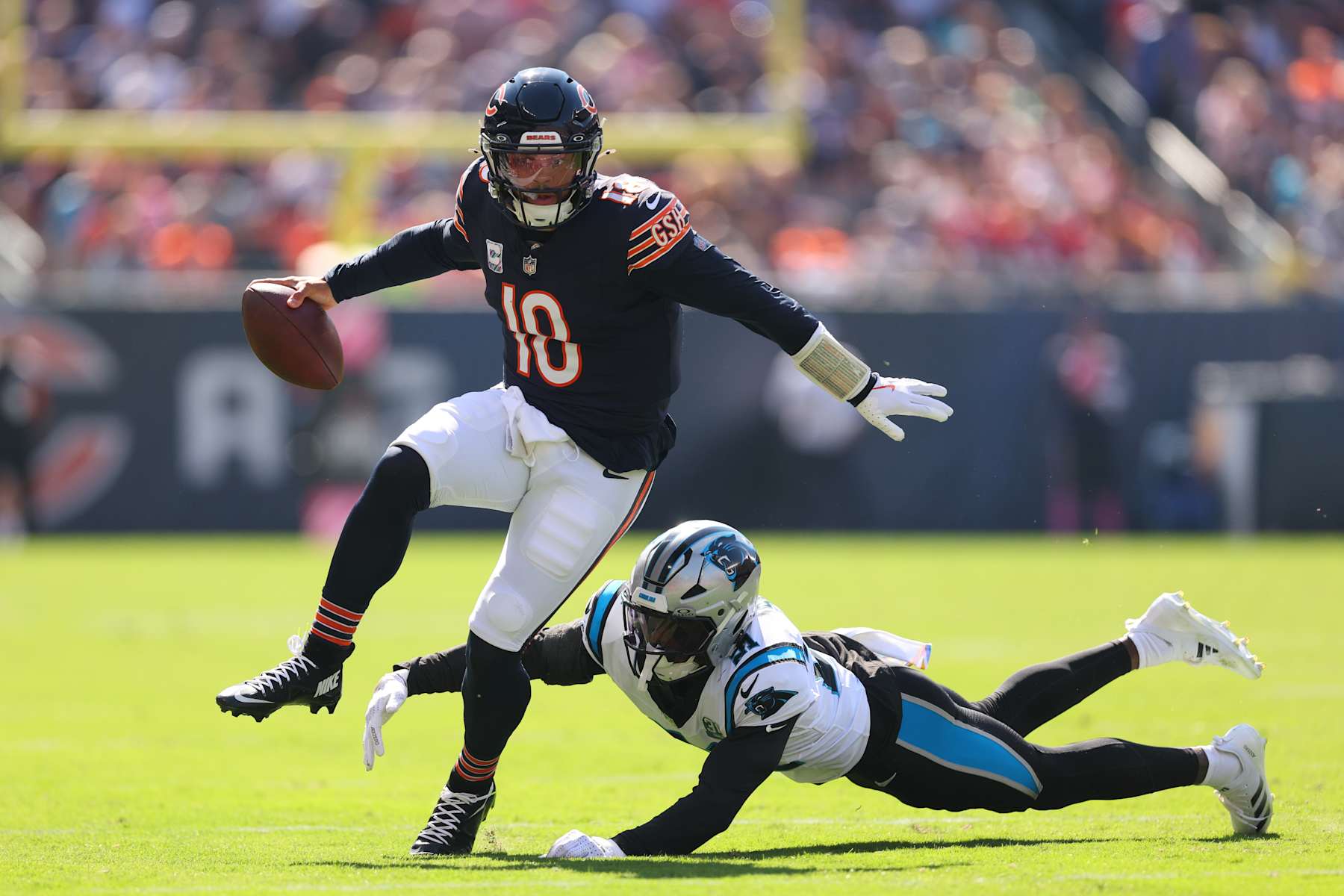 CHICAGO, ILLINOIS - OCTOBER 06: Caleb Williams #18 of the Chicago Bears breaks a tackle from Nick Scott #21 of the Carolina Panthers during the second quarter at Soldier Field on October 06, 2024 in Chicago, Illinois. (Photo by Michael Reaves/Getty Images)