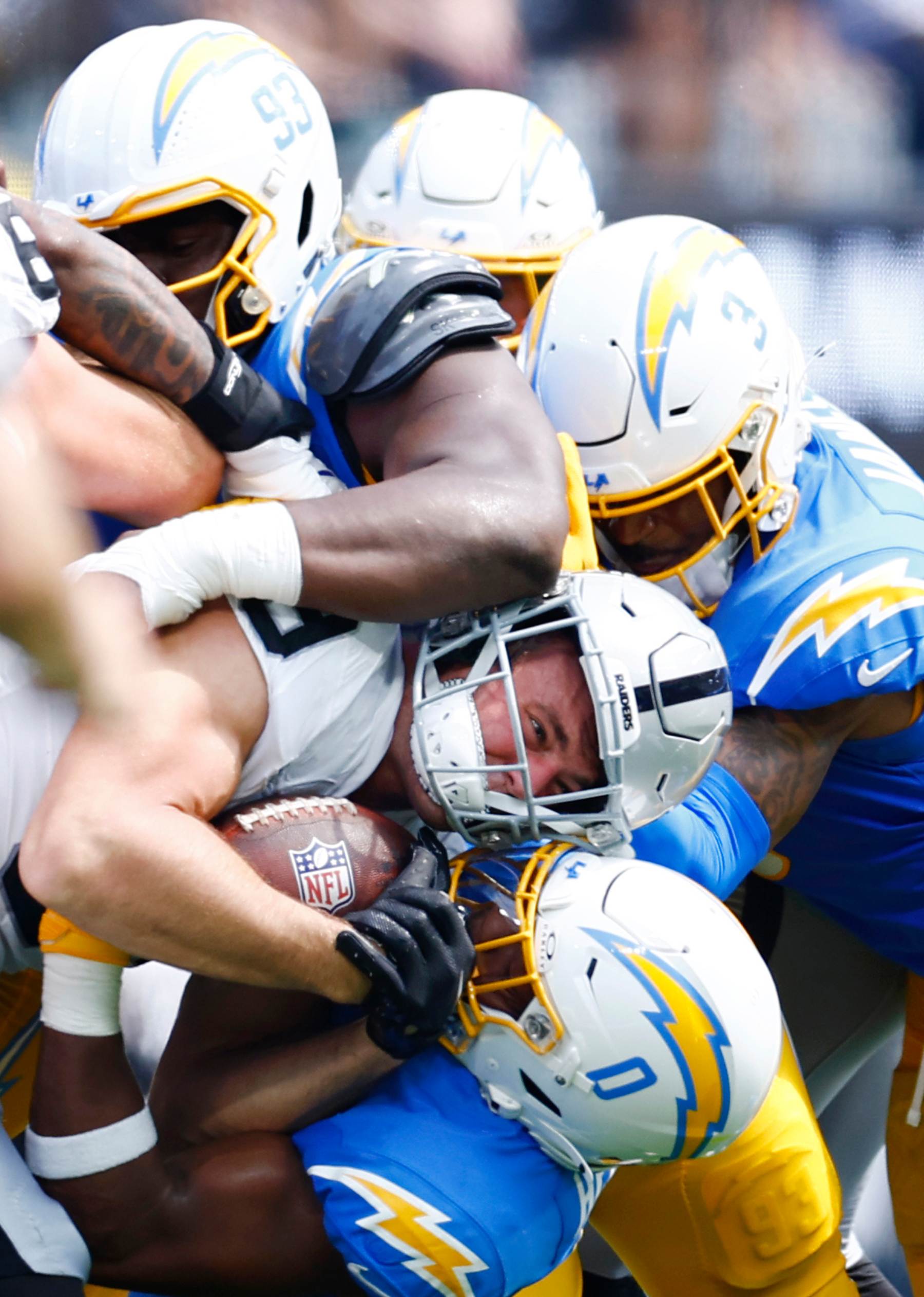 Raiders tight end Brock Bowers being tackled by a host of Chargers defenders. 