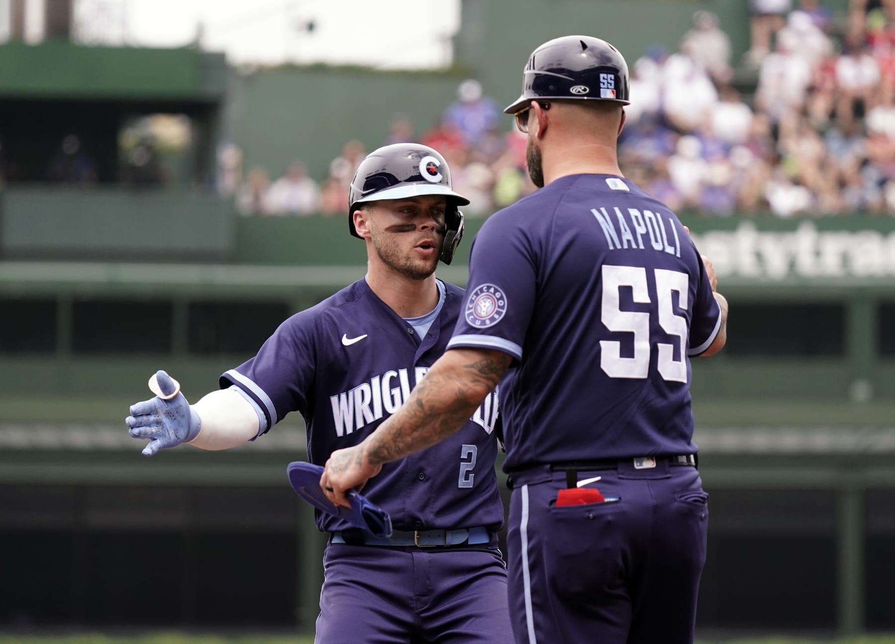 CHICAGO, ILLINOIS - JUNE 30: Nico Hoerner (L) #2 of the Chicago Cubs is congratulated by first base coach Mike Napoli #55 of the Chicago Cubs following a single during the first inning against the Cleveland Guardians at Wrigley Field on June 30, 2023 in Chicago, Illinois. (Photo by Nuccio DiNuzzo/Getty Images)