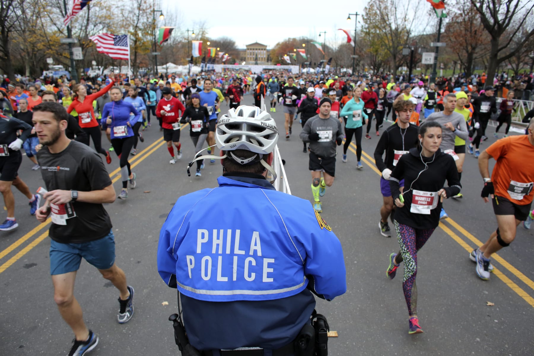 Philadelphia police Officer Andrew Schafer watches as runners make their way down the Benjamin Franklin Parkway in Philadelphia at the start of the Philadelphia Marathon, Sunday, Nov. 22, 2015. (AP Photo/ Joseph Kaczmarek)