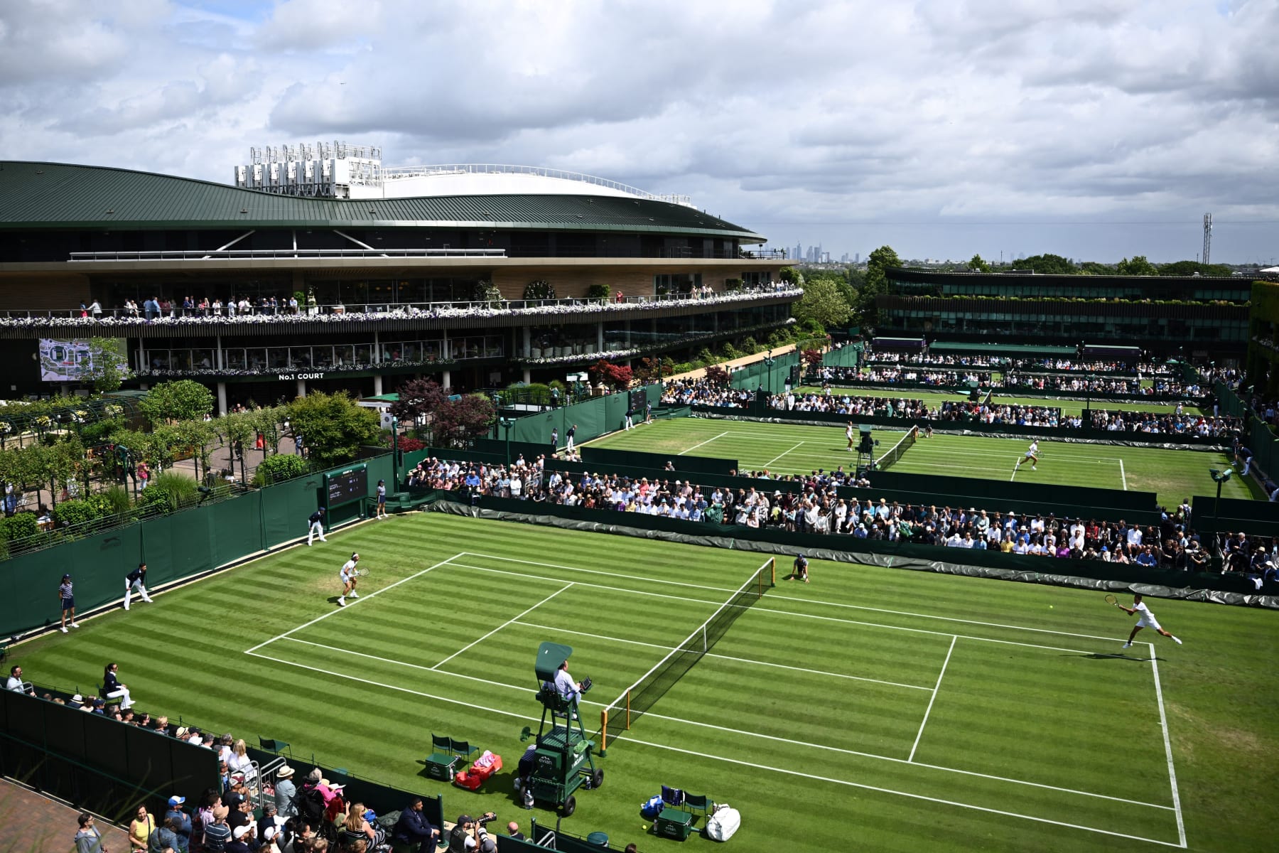 Italy's Lorenzo Musetti (L) returns the ball to Peru's Juan Pablo Varillas during their men's singles tennis match on court 14 with Centre Court on the background on the first day of the 2023 Wimbledon Championships at The All England Tennis Club in Wimbledon, southwest London, on July 3, 2023. (Photo by SEBASTIEN BOZON / AFP) / RESTRICTED TO EDITORIAL USE (Photo by SEBASTIEN BOZON/AFP via Getty Images)