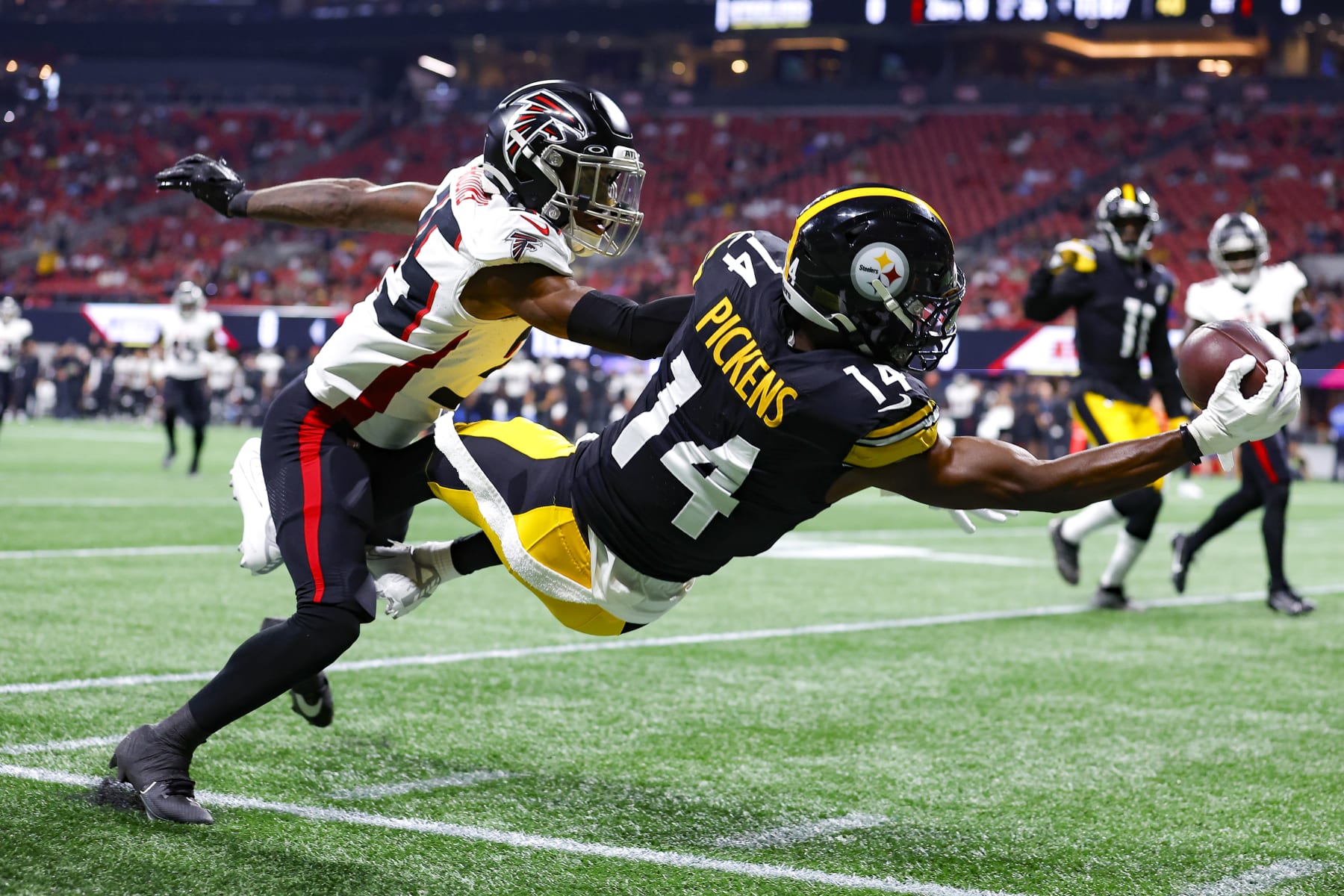 ATLANTA, GEORGIA - AUGUST 24: George Pickens #14 of the Pittsburgh Steelers leaps for a reception over Natrone Brooks #35 of the Atlanta Falcons during the first quarter of a preseason game at Mercedes-Benz Stadium on August 24, 2023 in Atlanta, Georgia. (Photo by Todd Kirkland/Getty Images)