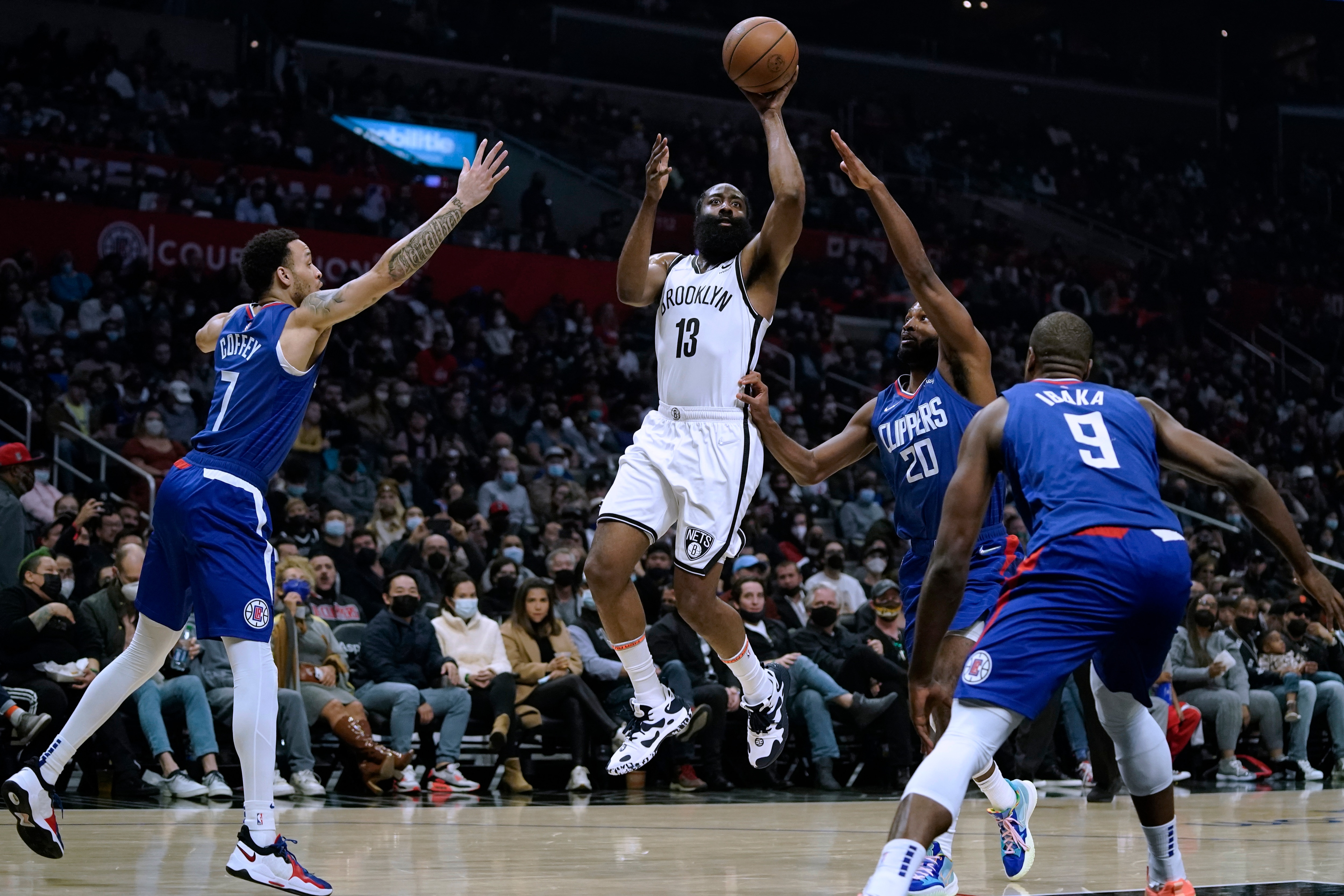 Brooklyn Nets' James Harden, center, shoots from between Los Angeles Clippers' Amir Coffey, left, and Justise Winslow during first half of an NBA basketball game Monday, Dec. 27, 2021, in Los Angeles. (AP Photo/Jae C. Hong)