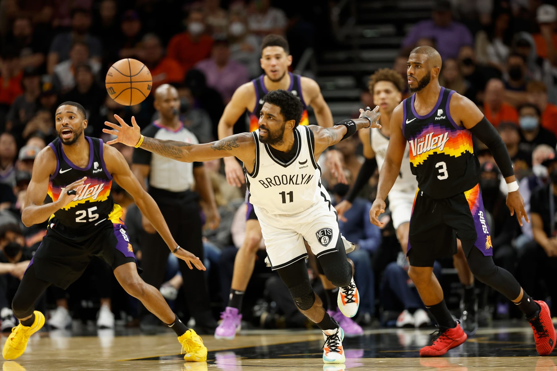 PHOENIX, ARIZONA - FEBRUARY 01:  Kyrie Irving #11 of the Brooklyn Nets attempts to control the ball ahead of Mikal Bridges #25 and Chris Paul #3 of the Phoenix Suns during the second half of the NBA game at Footprint Center on February 01, 2022 in Phoenix, Arizona. The Suns defeated the Nets 121-111. NOTE TO USER: User expressly acknowledges and agrees that, by downloading and or using this photograph, User is consenting to the terms and conditions of the Getty Images License Agreement. (Photo by Christian Petersen/Getty Images)