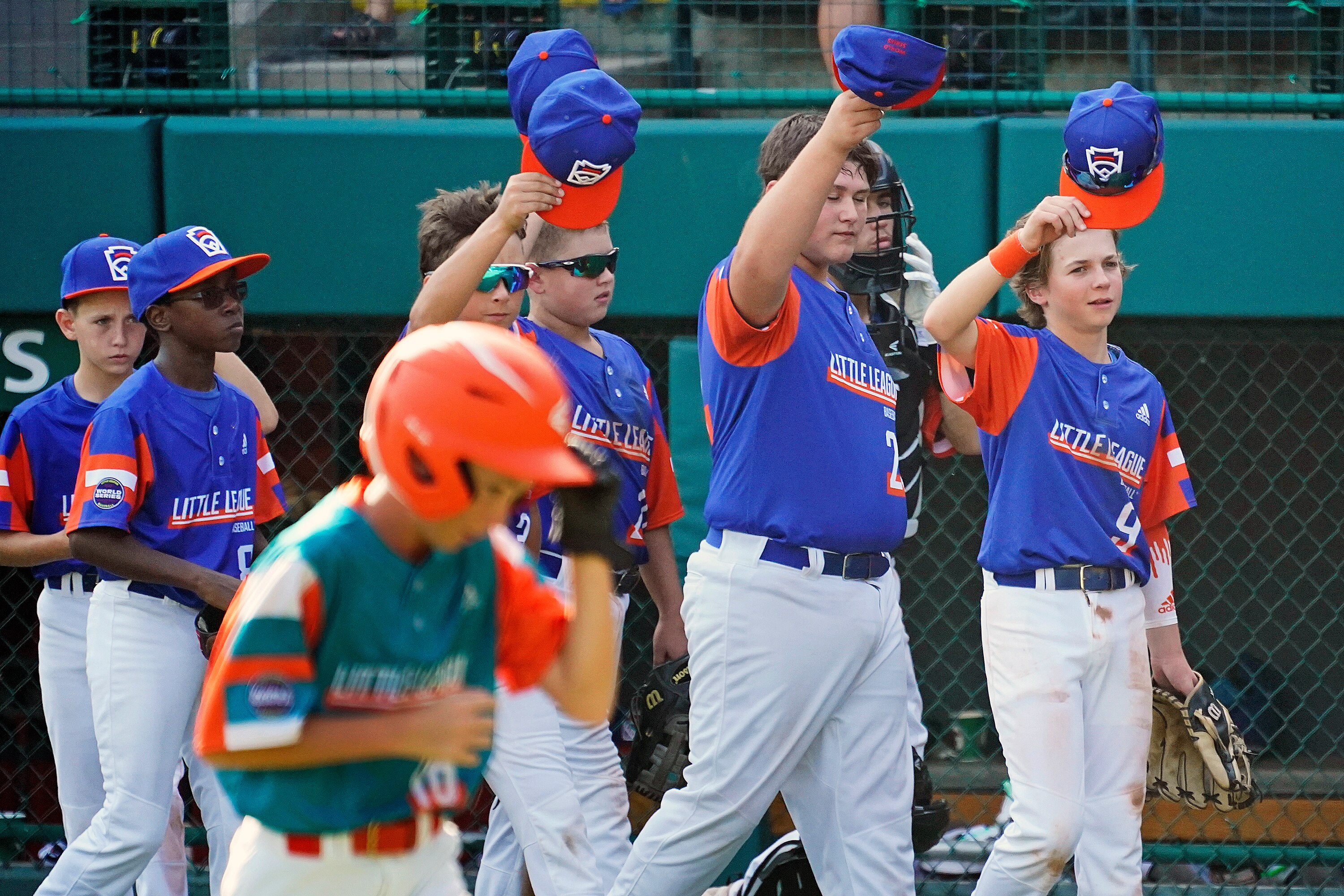Members of the Taylor, Mich., Little League team tip their caps to their opponent, the Palm City, Fla., team, at the conclusion of their baseball game at the Little League World Series in South Williamsport, Pa., Friday, Aug. 20, 2021. (AP Photo/Gene J. Puskar)