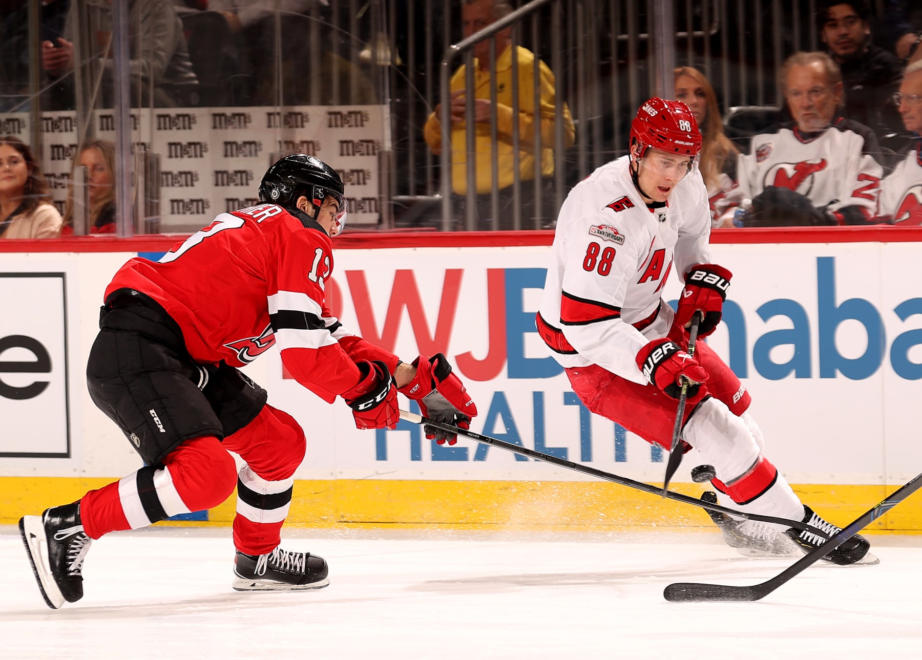 NEWARK, NEW JERSEY - MARCH 12: Nico Hischier #13 of the New Jersey Devils and Martin Necas #88 of the Carolina Hurricanes fight for the puck during the first period at Prudential Center on March 12, 2023 in Newark, New Jersey. (Photo by Elsa/Getty Images)