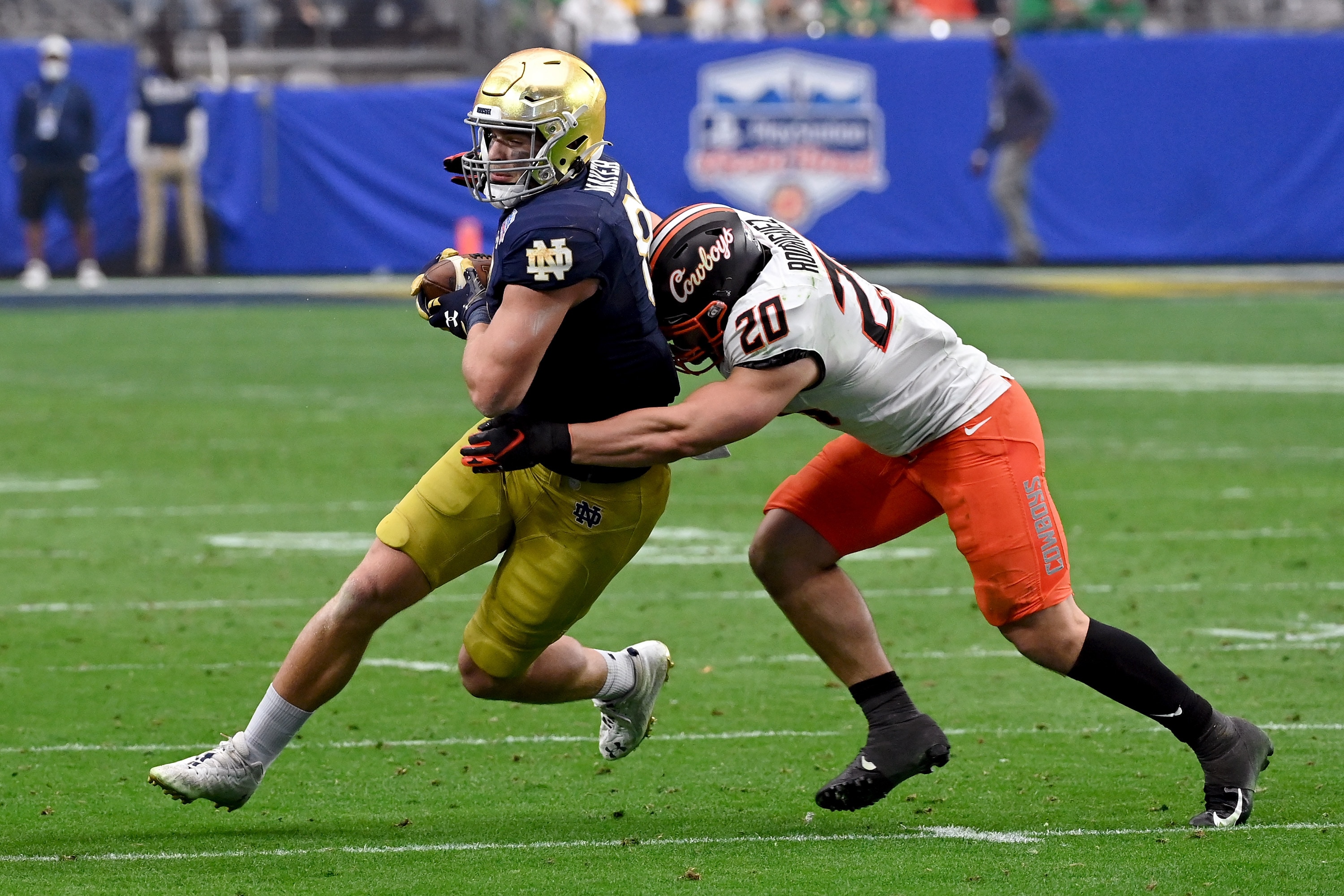 GLENDALE, ARIZONA - JANUARY 01: Michael Mayer #87 of the Notre Dame Fighting Irish runs with the ball while being tackled by Malcolm Rodriguez #20 of the Oklahoma State Cowboys in the second quarter during the PlayStation Fiesta Bowl at State Farm Stadium on January 01, 2022 in Glendale, Arizona. (Photo by Norm Hall/Getty Images)