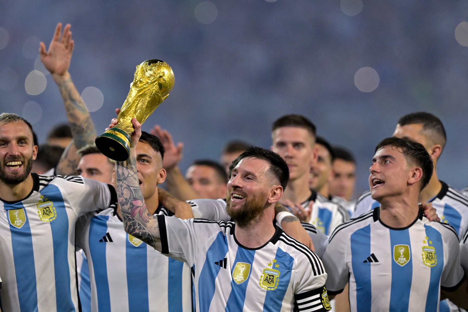 Argentina's forward Lionel Messi (C) raises a replica of the World Cup trophy next to his teammates during a recognition ceremony for the World Cup-winning players, following the friendly football match between Argentina and Curacao at the Madre de Ciudades stadium in Santiago del Estero, in northern Argentina, on March 28, 2023. (Photo by JUAN MABROMATA / AFP) (Photo by JUAN MABROMATA/AFP via Getty Images)