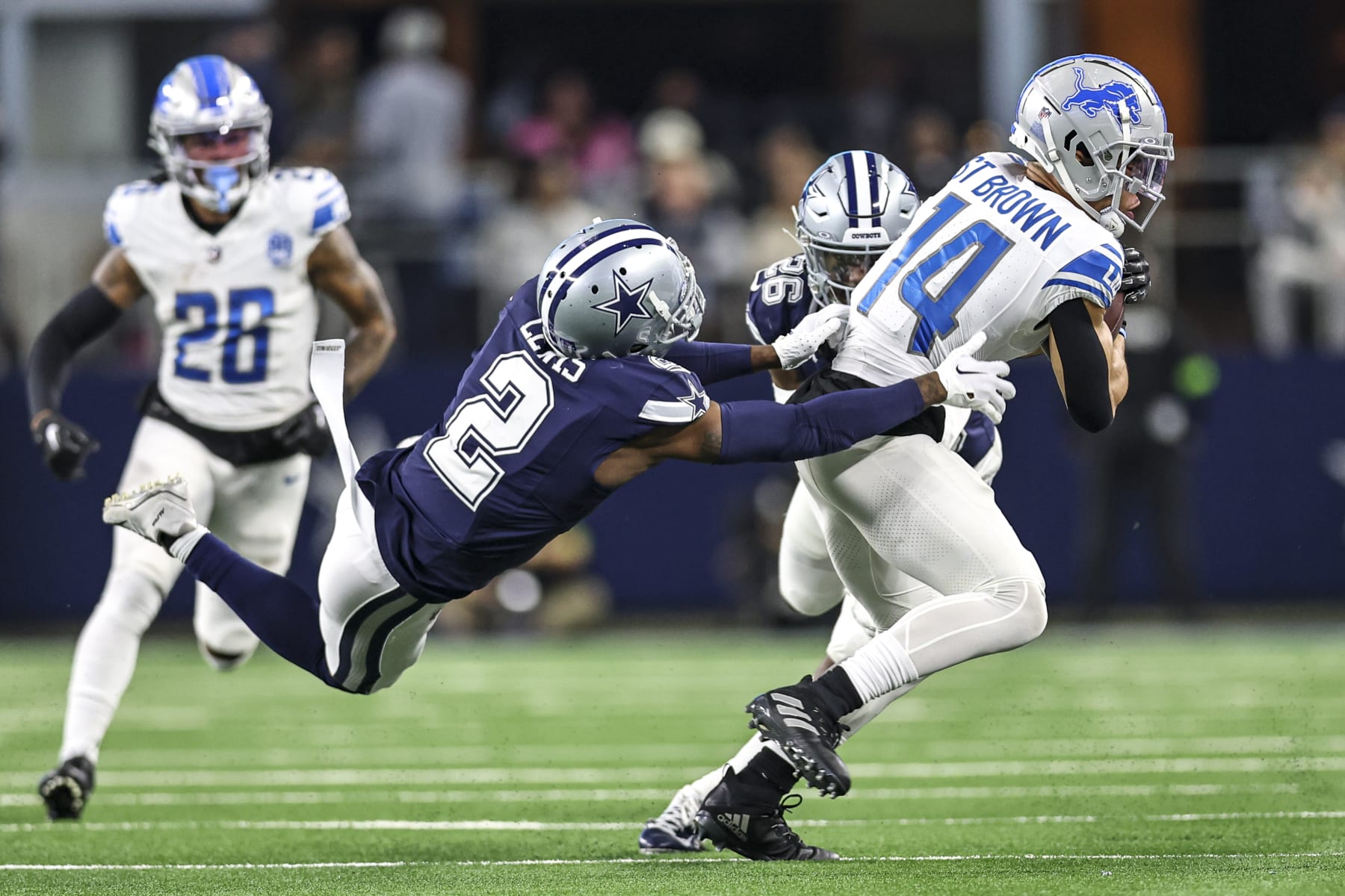 ARLINGTON, TX - DECEMBER 30: Detroit Lions wide receiver Amon-Ra St. Brown (14) catches a pass for a first down as Dallas Cowboys cornerback Jourdan Lewis (2) tries to tackle him during the game between the Dallas Cowboys and the Detroit Lions on December 30, 2023 at AT&T Stadium in Arlington, Texas. (Photo by Matthew Pearce/Icon Sportswire via Getty Images)