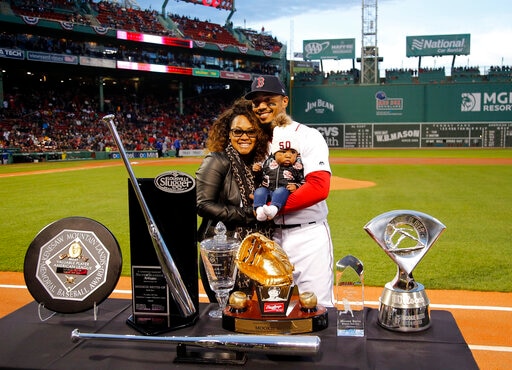 Boston Red Sox right fielder Mookie Betts stands with his daughter and his girlfriend Brianna Hammonds in front of his 2018 awards, including, a Rawlings Gold Glove, Silver Slugger and AL MVP before a baseball game between the Boston Red Sox and the Toronto Blue Jays Thursday, April 11, 2019, at Fenway Park in Boston. (AP Photo/Winslow Townson)