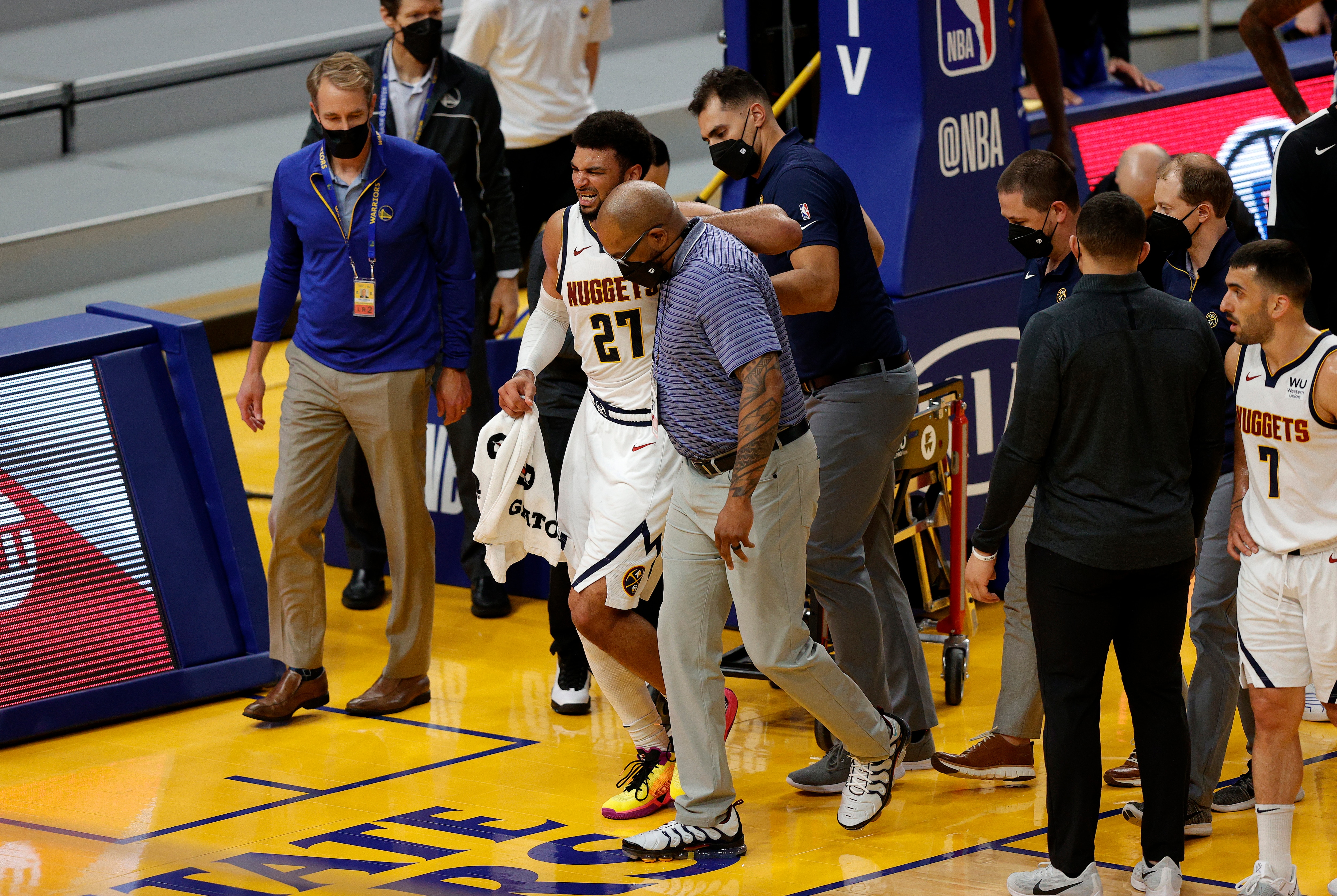 SAN FRANCISCO, CALIFORNIA - APRIL 12:  Jamal Murray #27 of the Denver Nuggets is helped off the court after an injury in their game against the Golden State Warriors at Chase Center on April 12, 2021 in San Francisco, California. NOTE TO USER: User expressly acknowledges and agrees that, by downloading and or using this photograph, User is consenting to the terms and conditions of the Getty Images License Agreement. (Photo by Ezra Shaw/Getty Images)