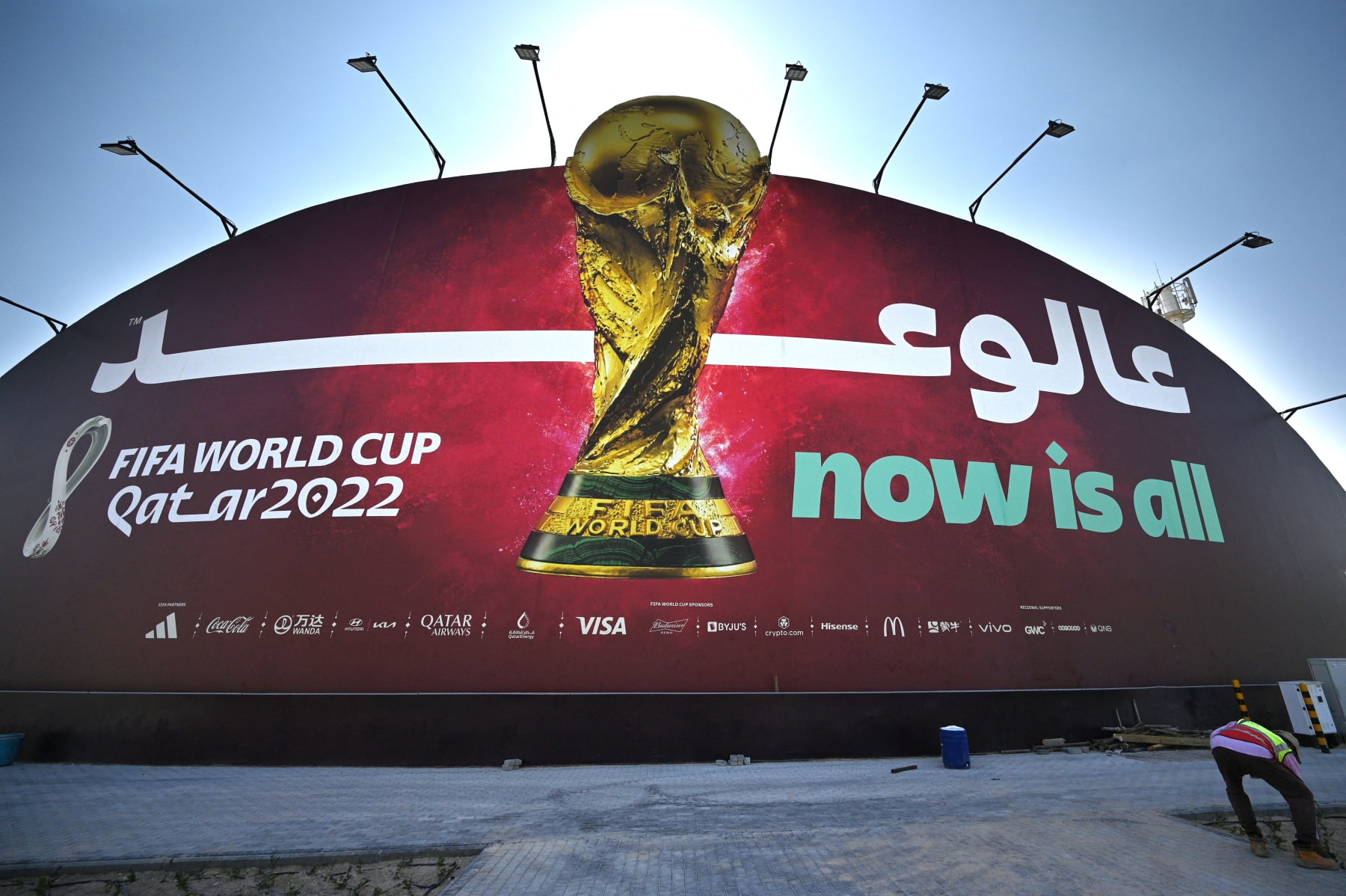 A man works in front of a Qatar 2022 FIFA World Cup football tournament billboard in Doha on October 29, 2022. (Photo by Gabriel BOUYS / AFP) (Photo by GABRIEL BOUYS/AFP via Getty Images)