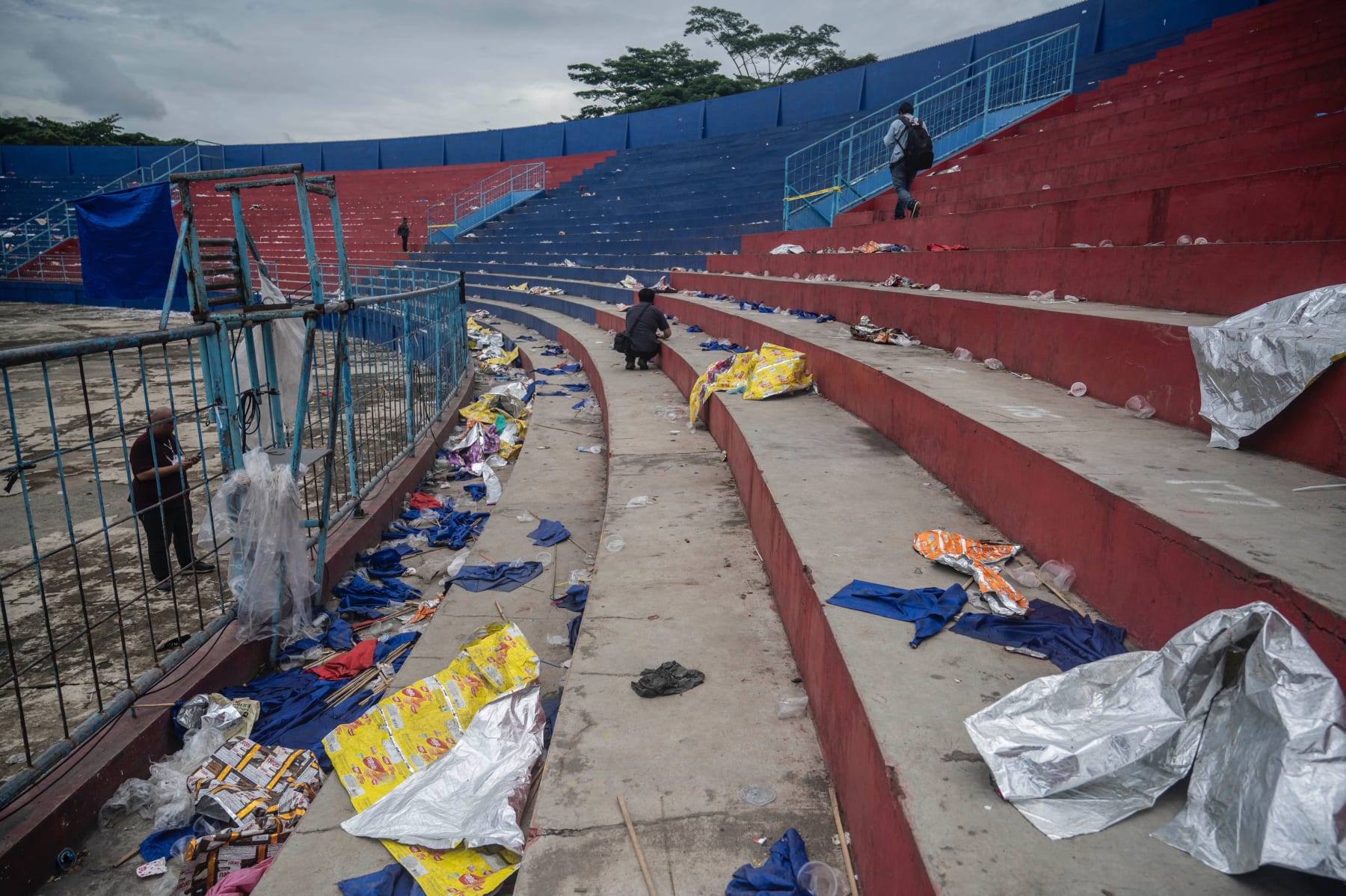 TOPSHOT - People walk amongst debris in the stands at Kanjuruhan stadium days after a deadly stampede following a football match in Malang, East Java on October 3, 2022. - Anger against police mounted in Indonesia on October 3 after at least 125 people were killed in one of the deadliest disasters in the history of football, when officers fired tear gas in a packed stadium, triggering a stampede. (Photo by Juni Kriswanto / AFP) (Photo by JUNI KRISWANTO/AFP via Getty Images)