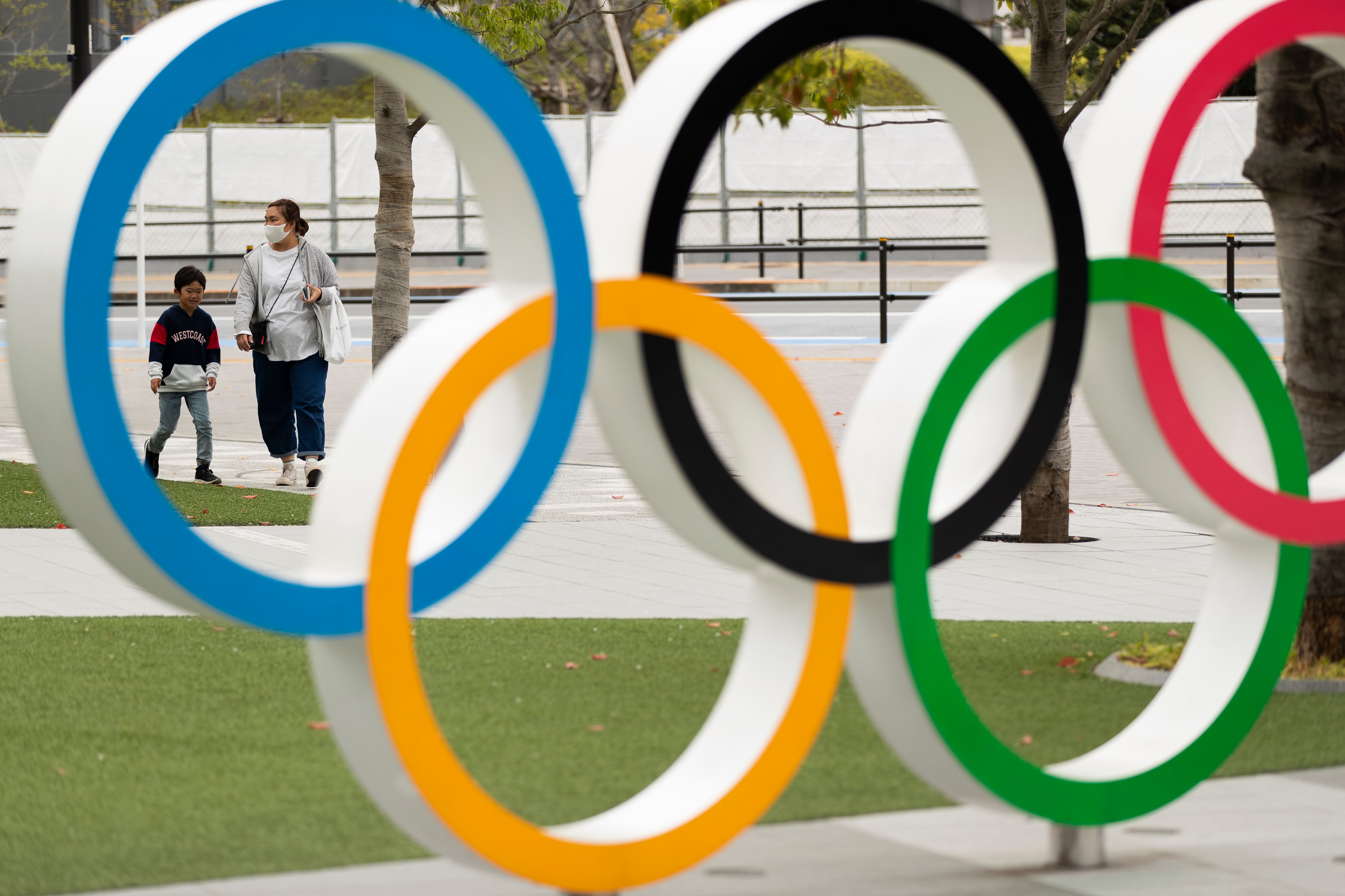 FILE - In this April 2, 2021, file photo, a mother and a boy walk by a display of the Olympic rings at the Japan Olympic Museum in Tokyo. Organizers and the International Olympic Committee pushed ahead Wednesday, April 28, 2021 with plans to open the postponed Tokyo Olympics in just under three months, unveiling the latest set of rule books to show how the games can be held during a pandemic. (AP Photo/Hiro Komae, File)
