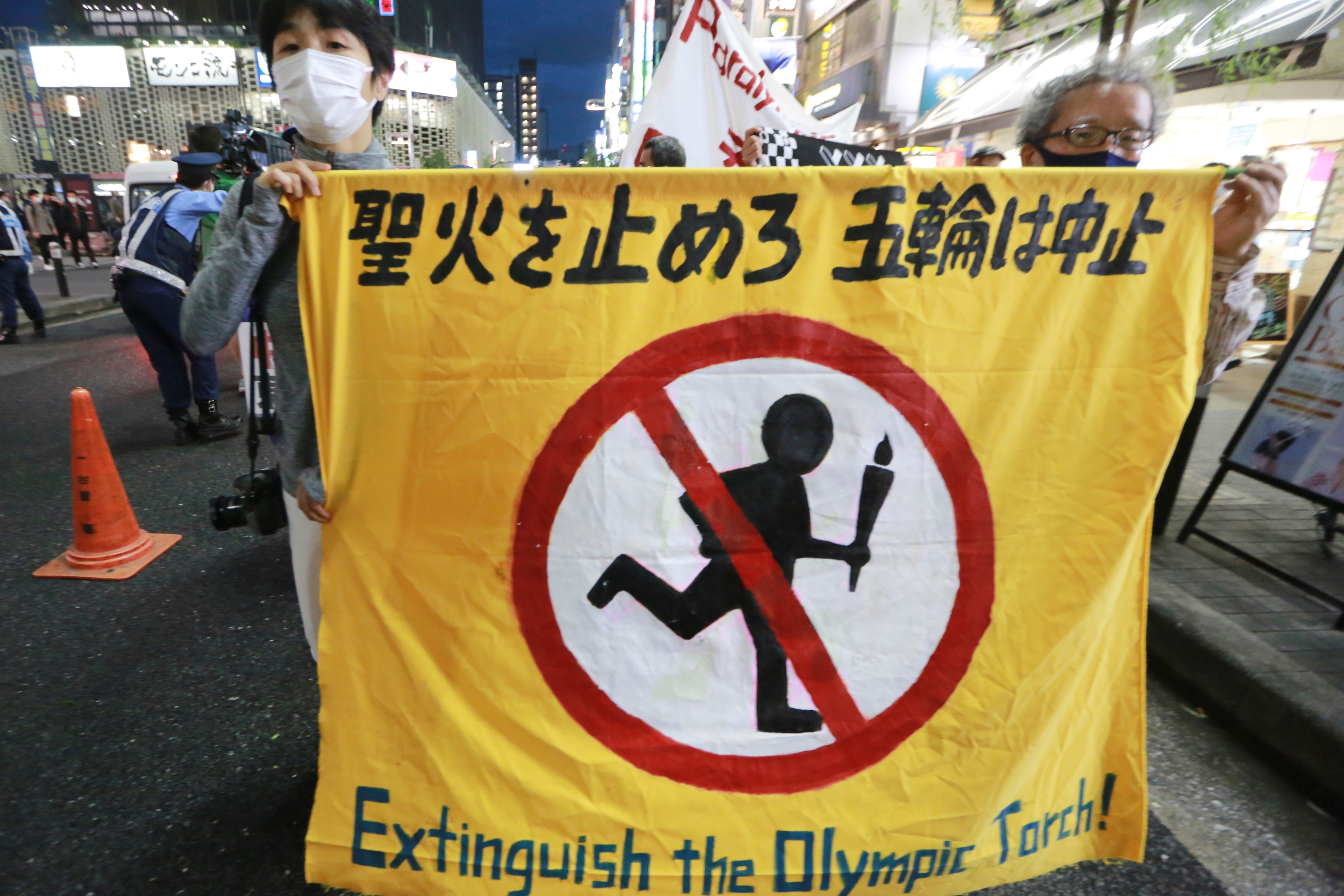 People carry a banner reading "Extinguish the Olympic torch" during a march, calling for the cancellation of the 2020 Tokyo Olympics to be held in the middle of a pandemic, in Tokyo, Monday, May 17, 2021. (AP Photo/Koji Sasahara)