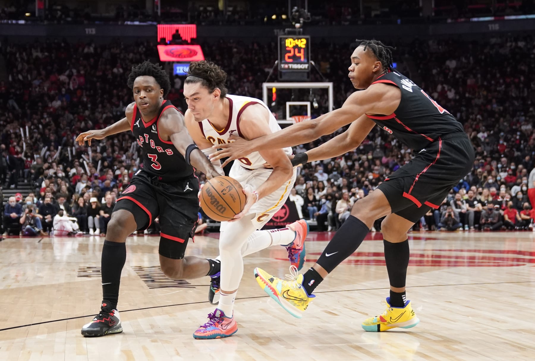 TORONTO, ON - NOVEMBER 5: Cedi Osman #16 of the Cleveland Cavaliers is defended by Scottie Barnes #4 and OG Anunoby #3 of the Toronto Raptors during the second half of their basketball game at the Scotiabank Arena on November 5, 2021 in Toronto, Ontario, Canada. NOTE TO USER: User expressly acknowledges and agrees that, by downloading and/or using this Photograph, user is consenting to the terms and conditions of the Getty Images License Agreement. (Photo by Mark Blinch/Getty Images)