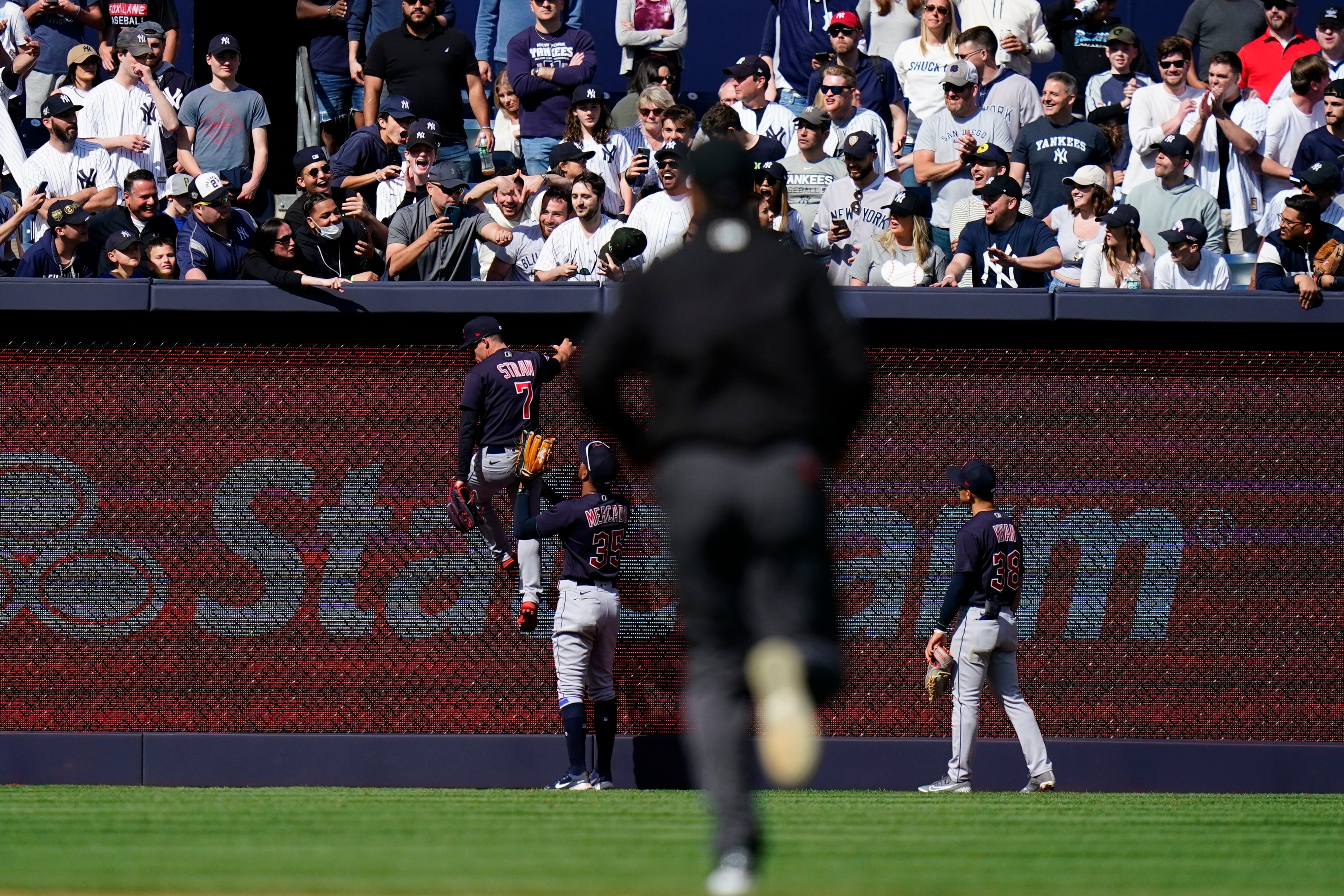 An umpire heads to left field as Cleveland Guardians' Oscar Mercado (35) restrains Myles Straw (7) during an altercation with fans during the ninth inning of a baseball game against the New York Yankees Saturday, April 23, 2022, in New York. The Yankees won 5-4. (AP Photo/Frank Franklin II)