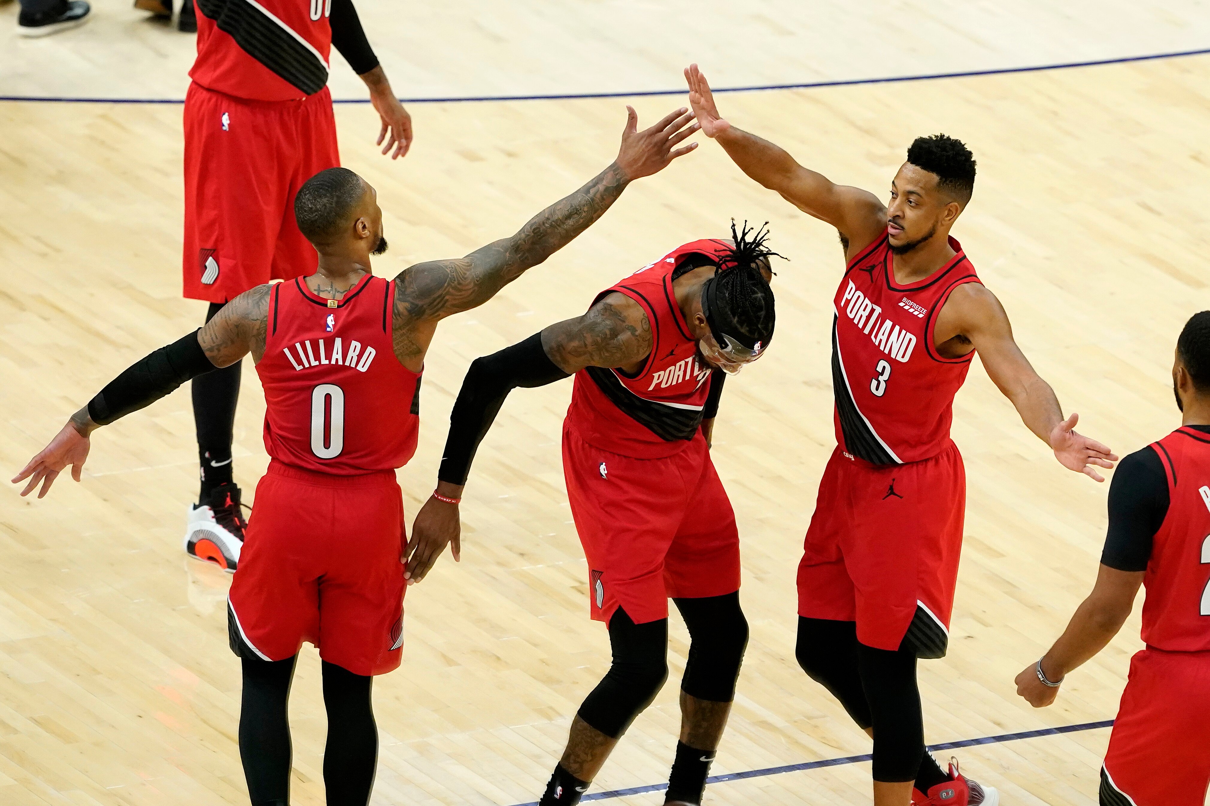 Portland Trail Blazers guard Damian Lillard (0) high fives guard CJ McCollum (3) over forward Robert Covington during the second half of an NBA basketball game against the Phoenix Suns, Thursday, May 13, 2021, in Phoenix. (AP Photo/Matt York)
