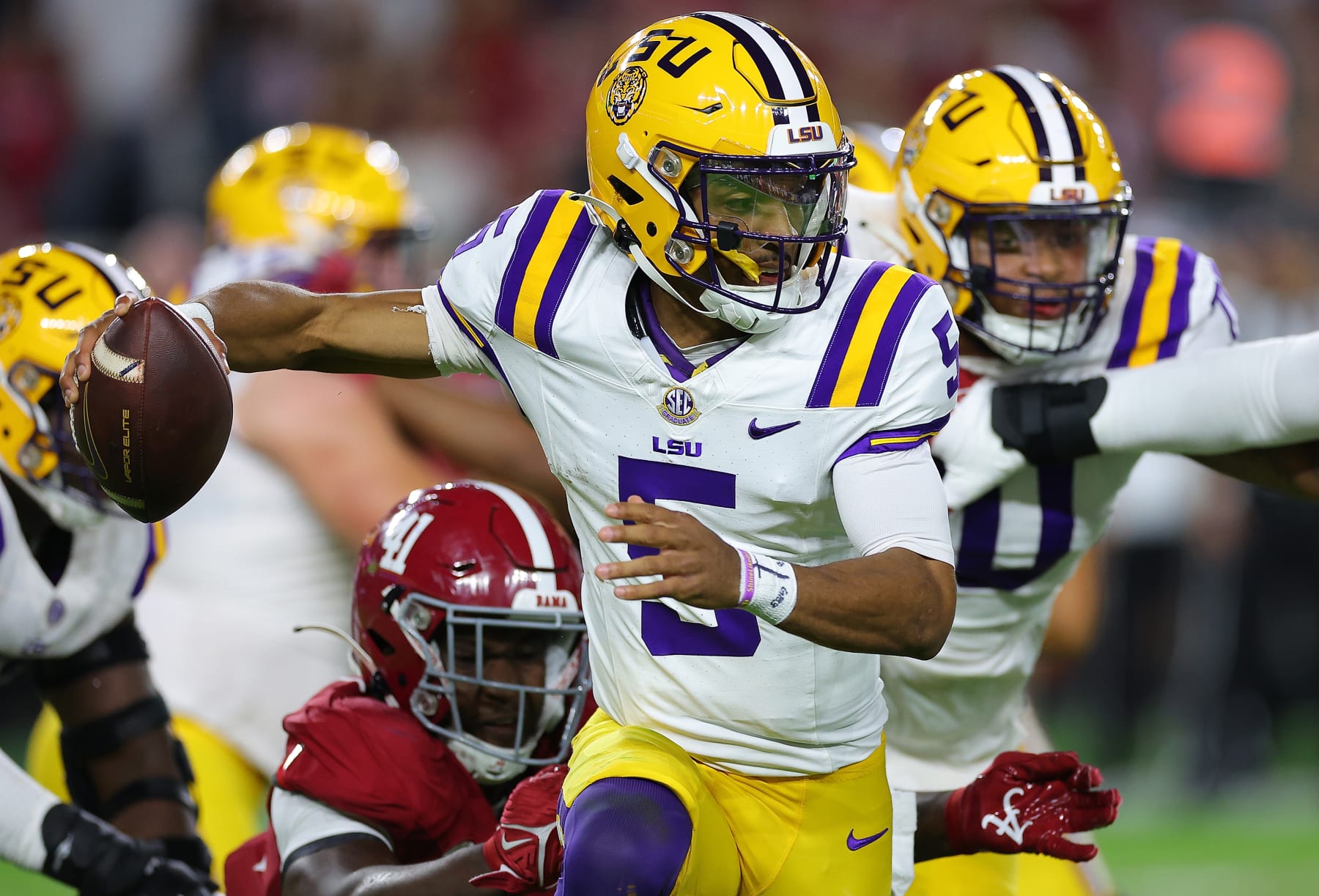 TUSCALOOSA, ALABAMA - NOVEMBER 04:  Jayden Daniels #5 of the LSU Tigers breaks a tackle as he rushes away from Chris Braswell #41 of the Alabama Crimson Tide during the second quarter at Bryant-Denny Stadium on November 04, 2023 in Tuscaloosa, Alabama.  (Photo by Kevin C. Cox/Getty Images)