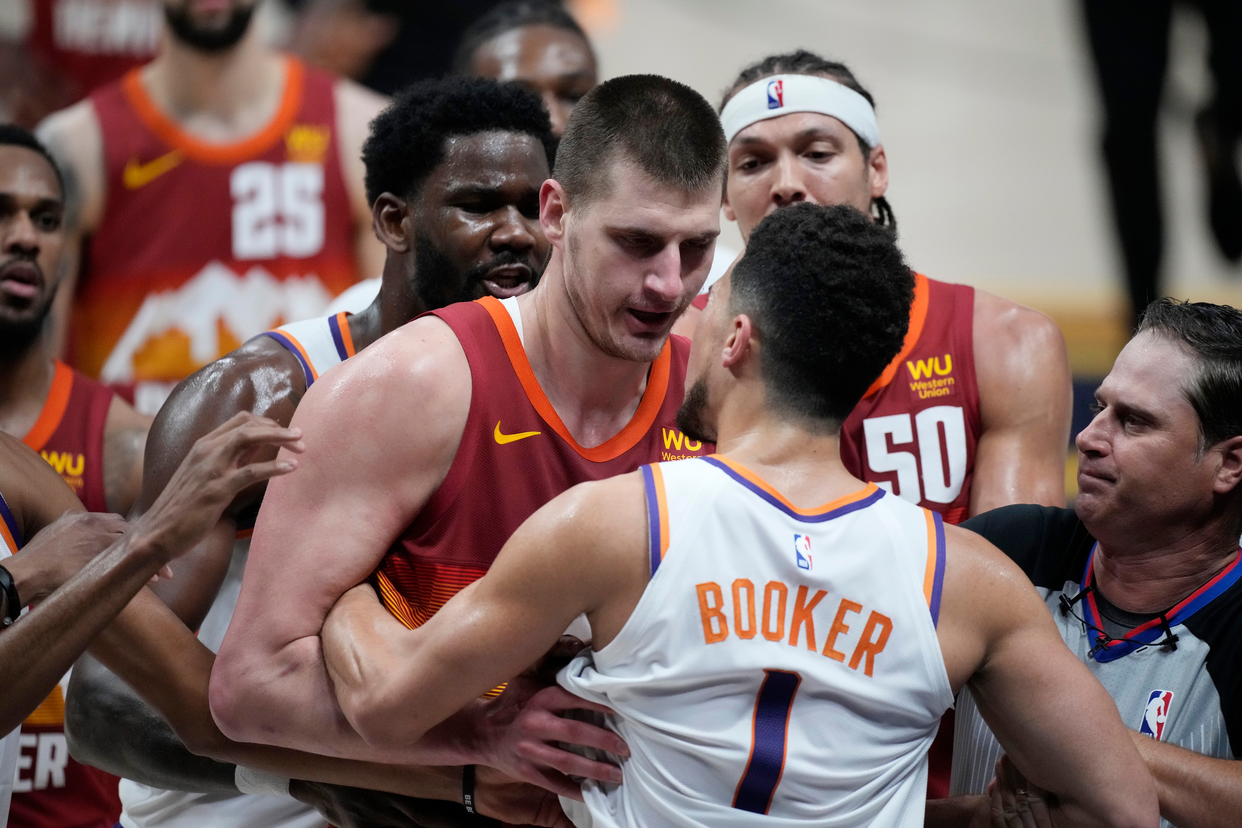 Referee David Guthrie, right, struggles to keep Denver Nuggets center Nikola Jokic, back, from fighting with Phoenix Suns guard Devin Booker in the second half of Game 4 of an NBA second-round playoff series Sunday, June 13, 2021, in Denver. (AP Photo/David Zalubowski)