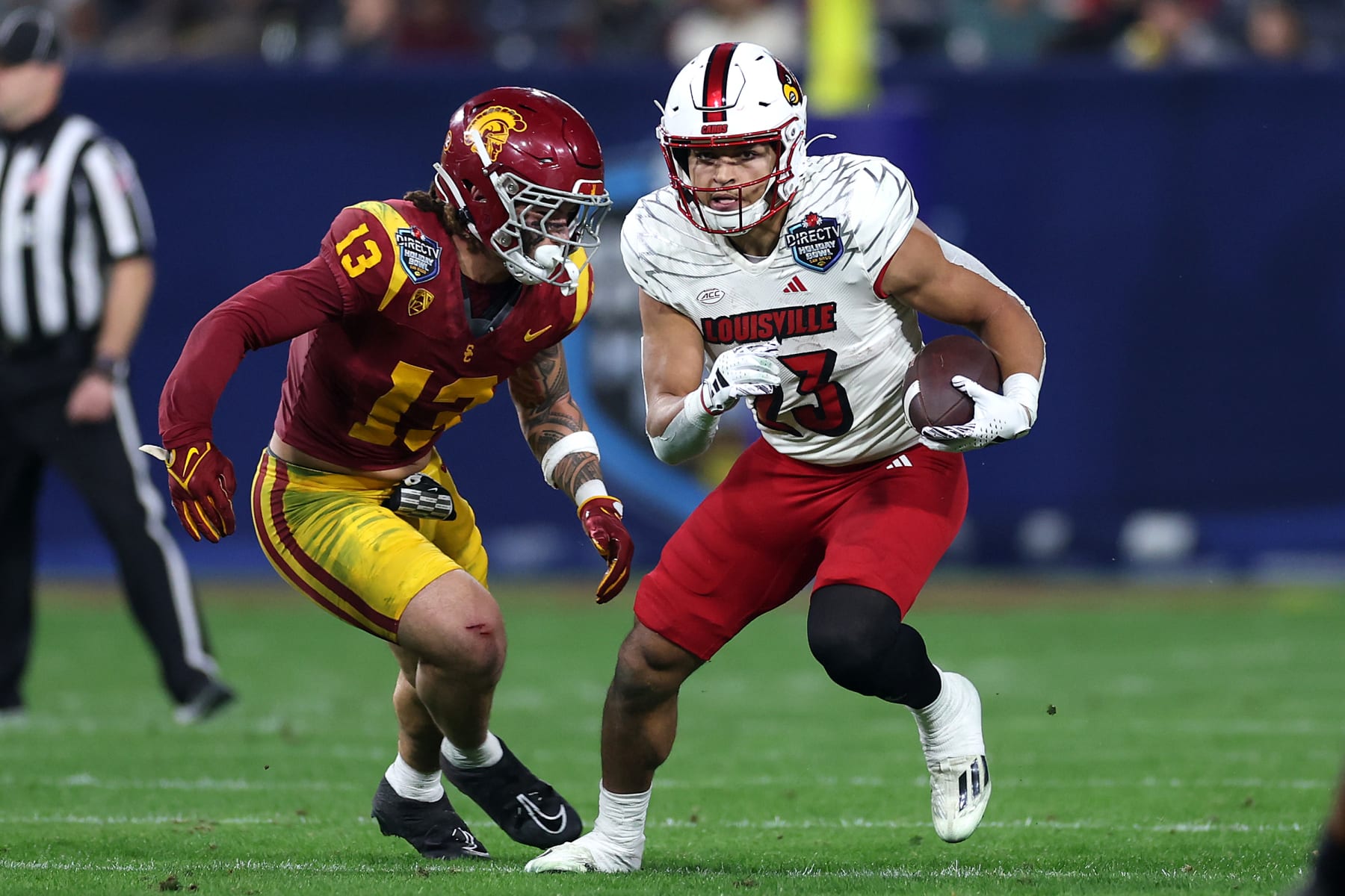 SAN DIEGO, CALIFORNIA - DECEMBER 27: Isaac Guerendo #23 of the Louisville Cardinals rushes the ball past the defense of Mason Cobb #13 of the USC Trojans during the first half of the DIRECTV Holiday Bowl at Petco Park on December 27, 2023 in San Diego, California. (Photo by Sean M. Haffey/Getty Images)