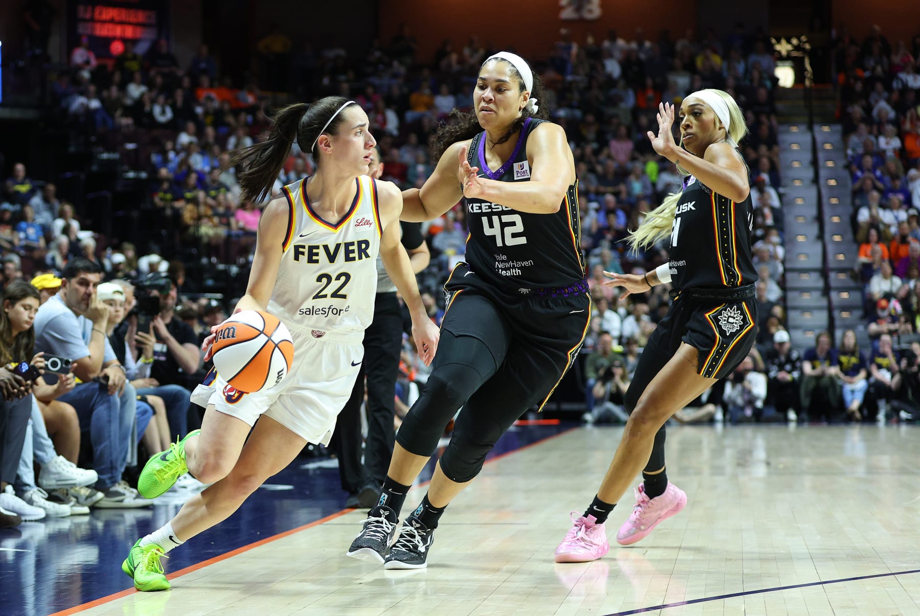 UNCASVILLE, CT - MAY 14: Indiana Fever guard Caitlin Clark (22) doubled-teamed by Connecticut Sun forward Brionna Jones (42) and Connecticut Sun guard DiJonai Carrington (21) during a WNBA game between Indiana Fever and Connecticut Sun on May 14, 2024, at Mohegan Sun Arena in Uncasville, CT. (Photo by M. Anthony Nesmith/Icon Sportswire via Getty Images)