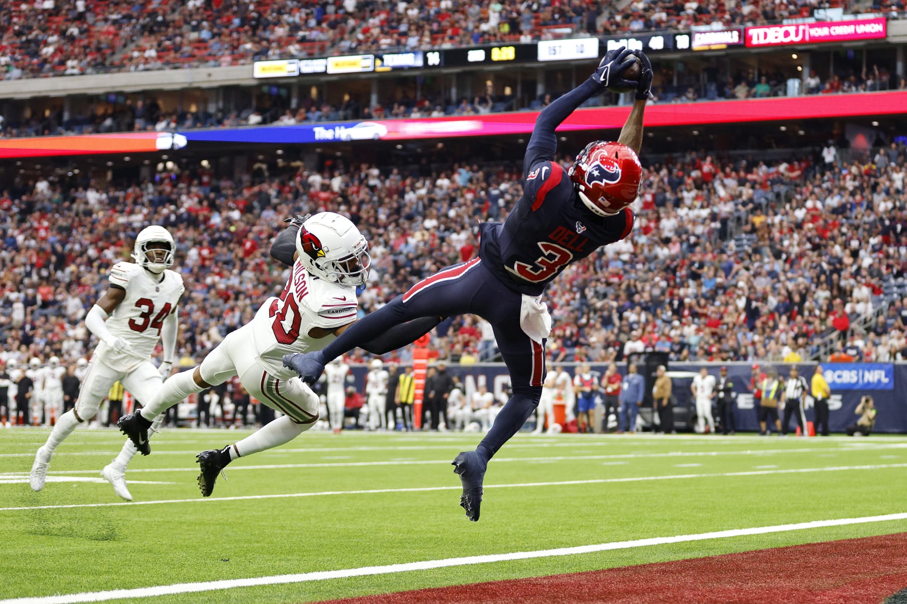HOUSTON, TEXAS - NOVEMBER 19: Tank Dell #3 of the Houston Texans catches a pass for a touchdown in front of Marco Wilson #20 of the Arizona Cardinals during the second quarter at NRG Stadium on November 19, 2023 in Houston, Texas. (Photo by Tim Warner/Getty Images)
