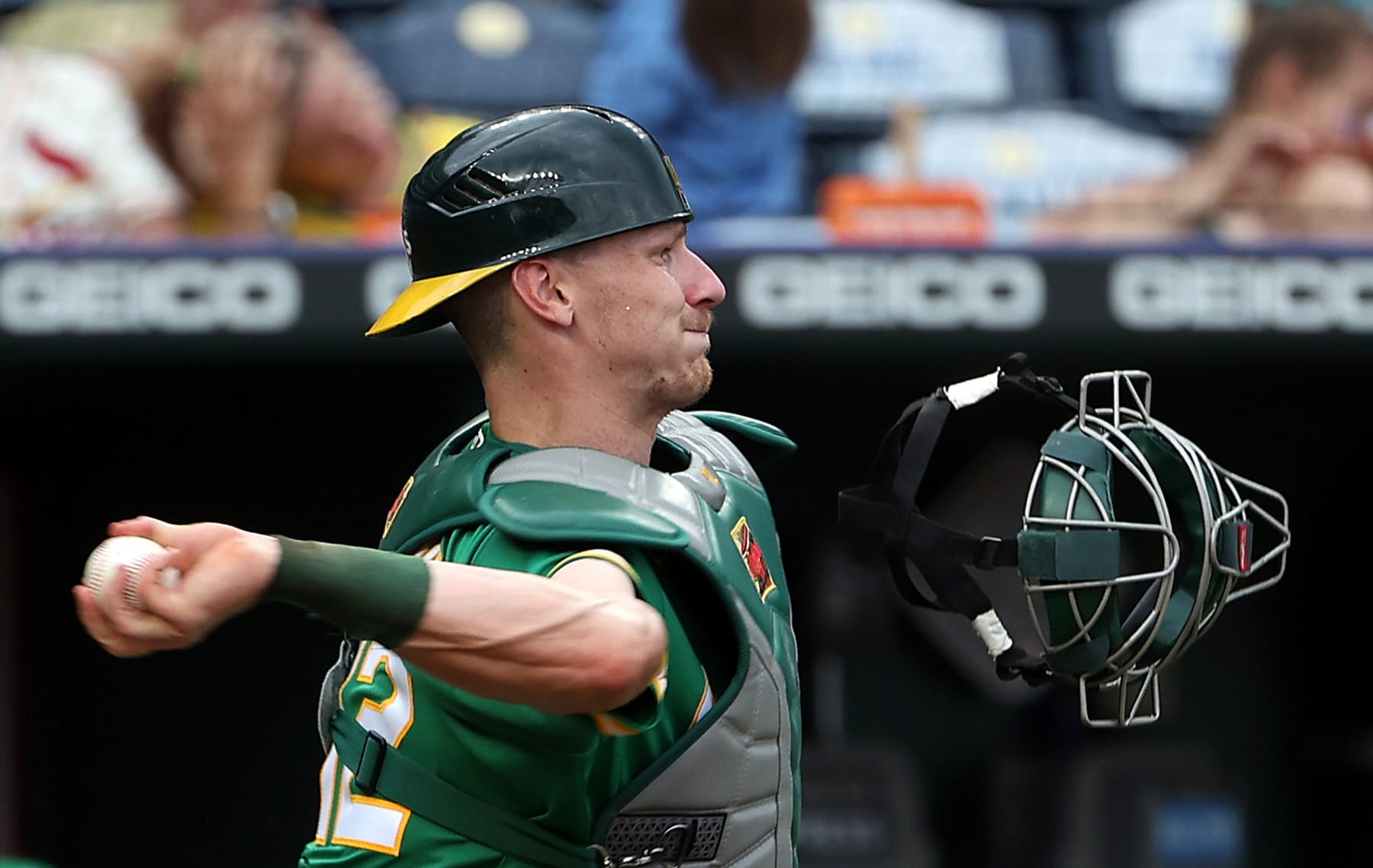 KANSAS CITY, MISSOURI - JUNE 25:  Catcher Sean Murphy #12 of the Oakland Athletics loses his mask as he throws toward third base during the 8th inning of the game against the Kansas City Royals at Kauffman Stadium on June 25, 2022 in Kansas City, Missouri. (Photo by Jamie Squire/Getty Images)