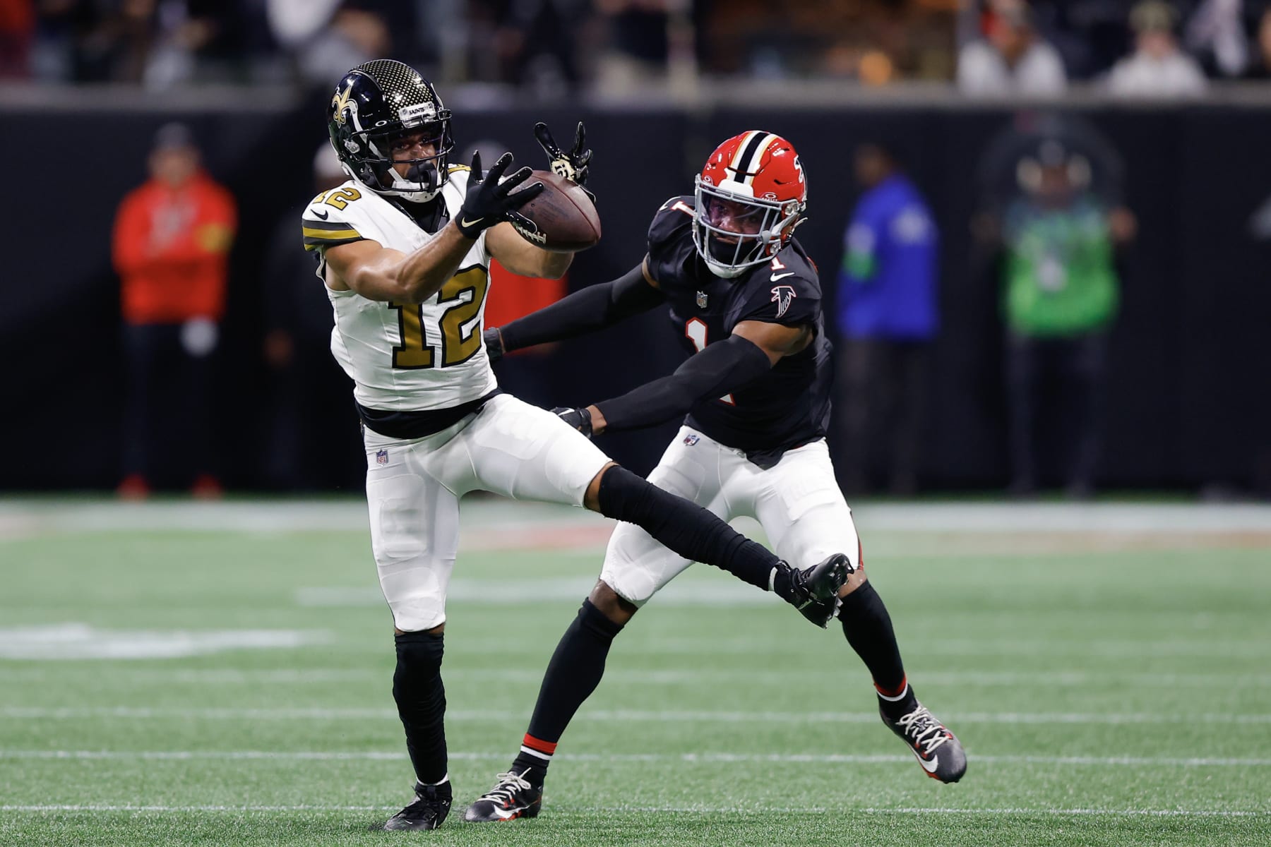 ATLANTA, GEORGIA - NOVEMBER 26: Chris Olave #12 of the New Orleans Saints catches the ball as he is defended by Jeff Okudah #1 of the Atlanta Falcons in the first quarter of the game at Mercedes-Benz Stadium on November 26, 2023 in Atlanta, Georgia. (Photo by Todd Kirkland/Getty Images)