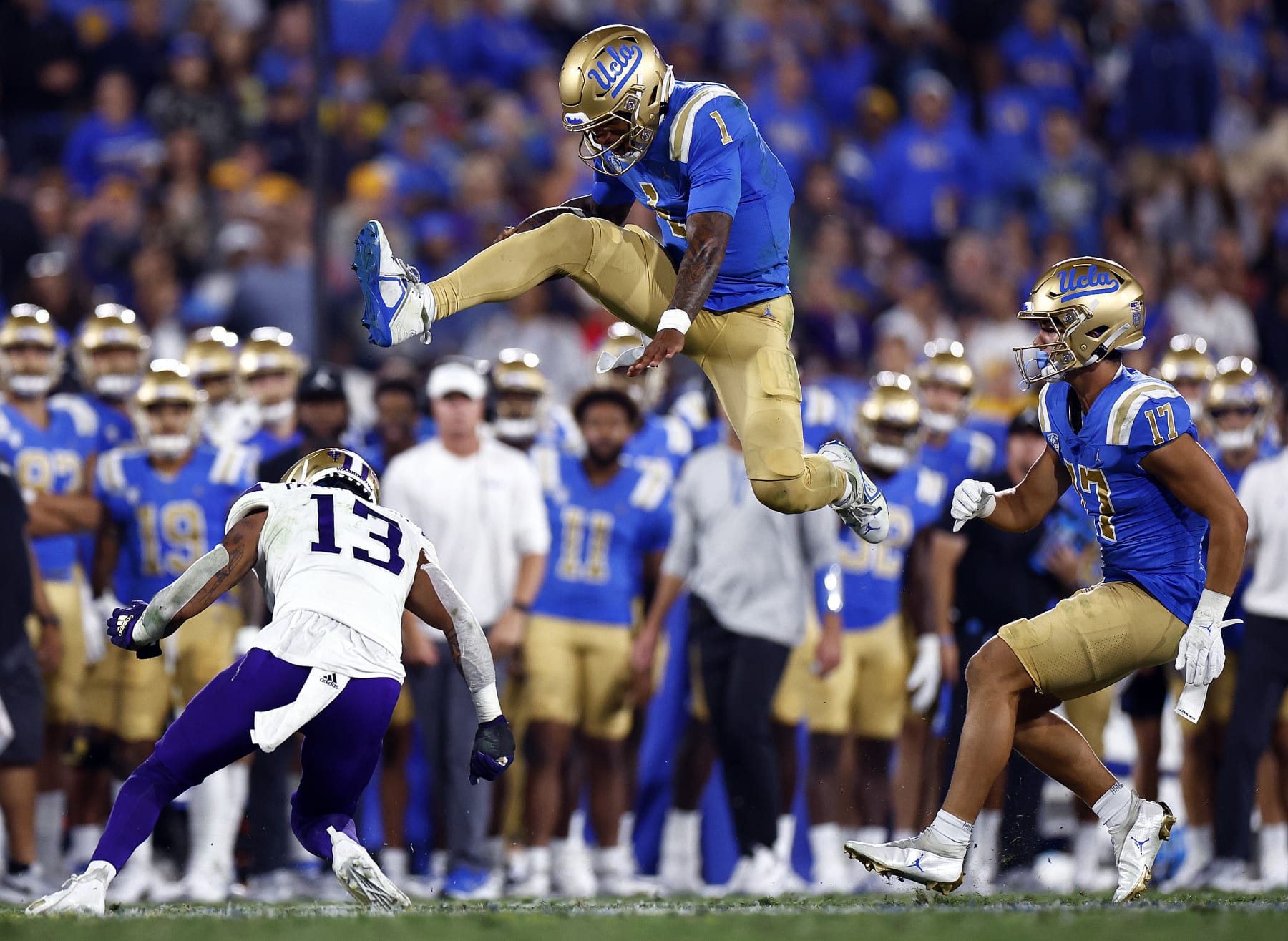 PASADENA, CALIFORNIA - SEPTEMBER 30:  Dorian Thompson-Robinson #1 of the UCLA Bruins jumps over Kamren Fabiculanan #13 of the Washington Huskies in the second quarter at Rose Bowl Stadium on September 30, 2022 in Pasadena, California. (Photo by Ronald Martinez/Getty Images)